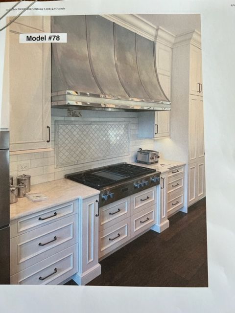 Elegant kitchen with stainless range hood, black stove, white cabinets, and light tile backsplash
