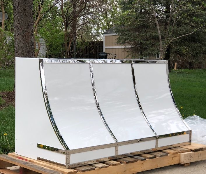 White curved metal panels on a wooden pallet outdoors in a grassy yard