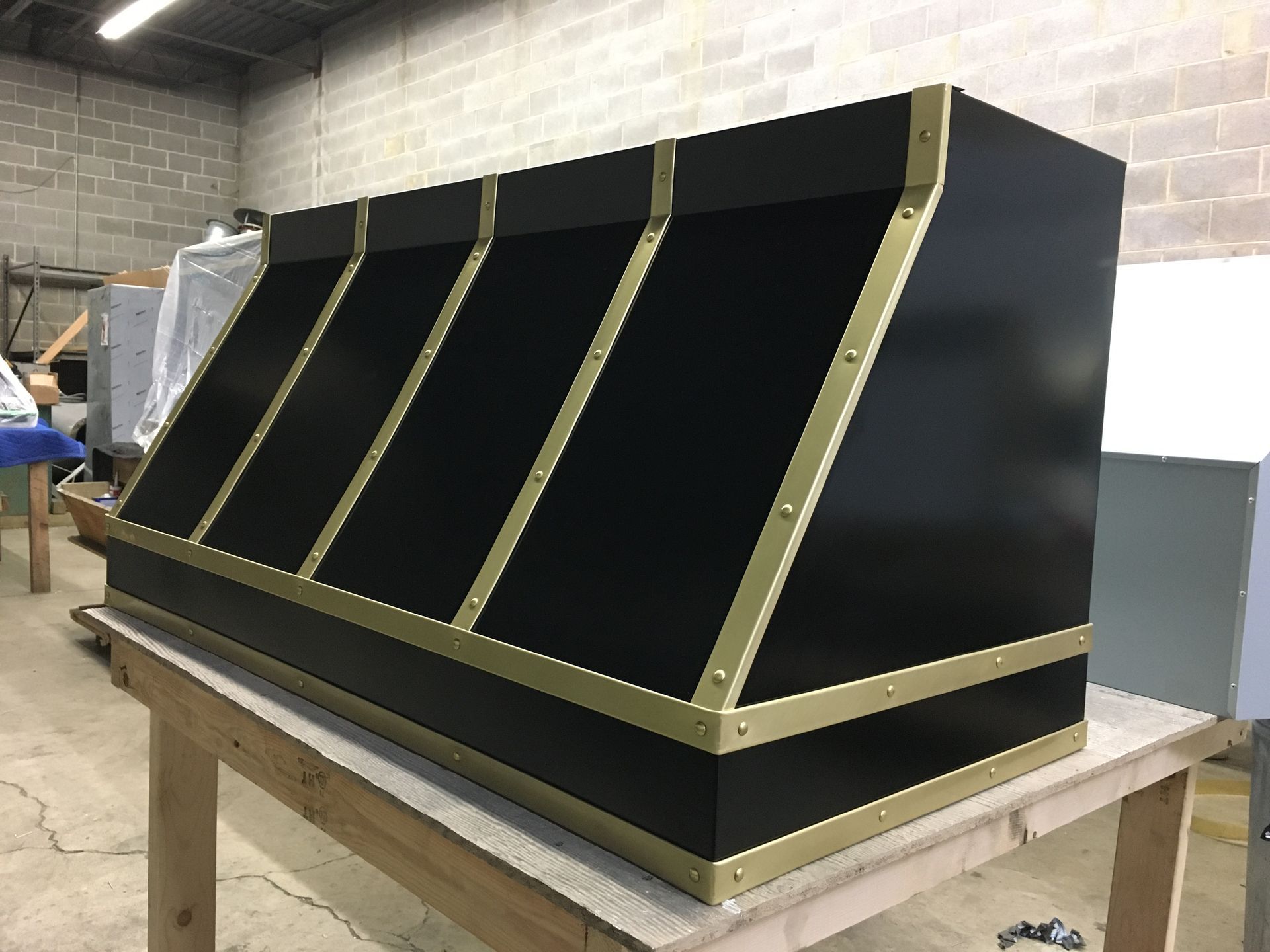 Black-and-gold slanted display cabinet on a workbench in a workshop