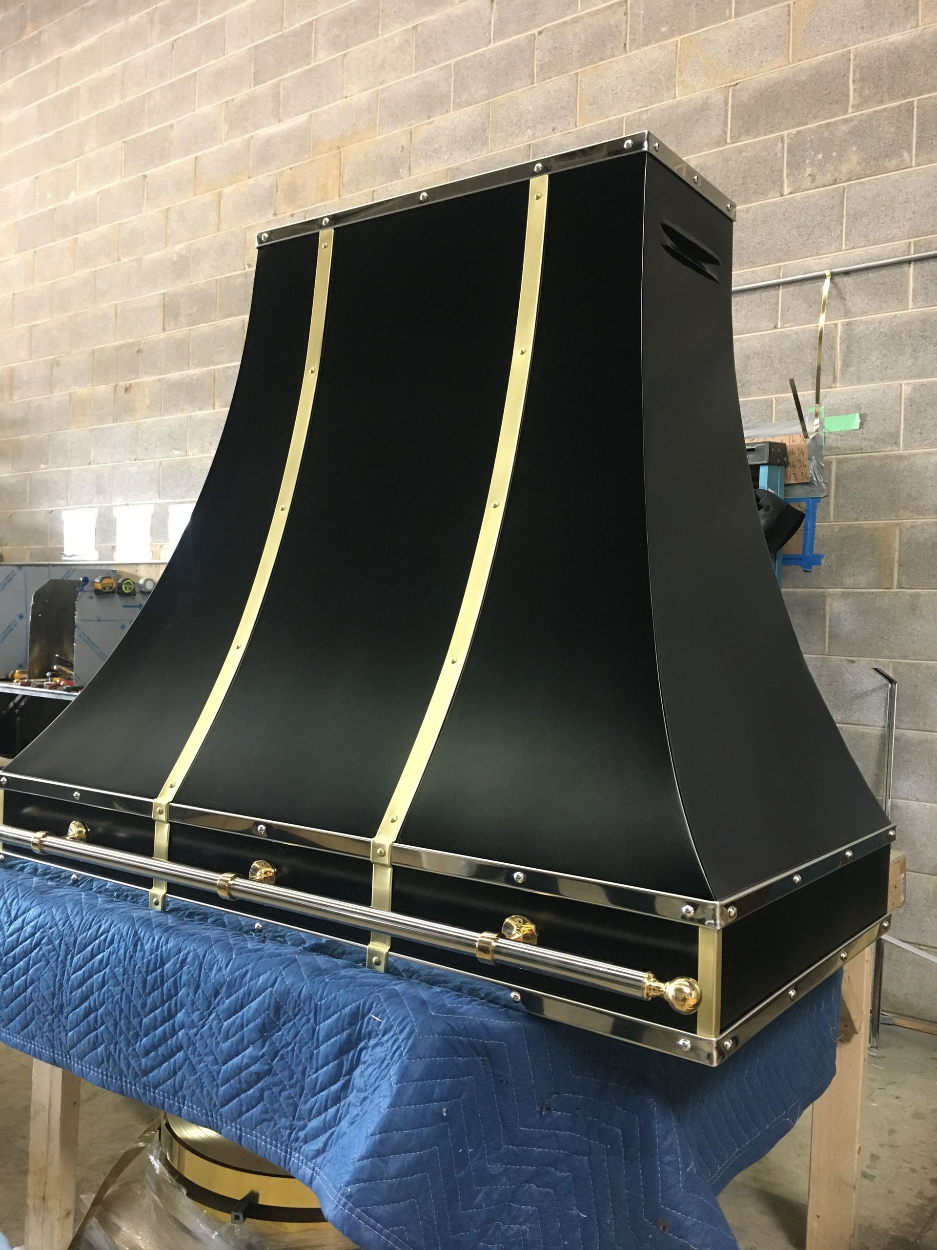 Black industrial machine housing with gold trim on a worktable in a workshop setting