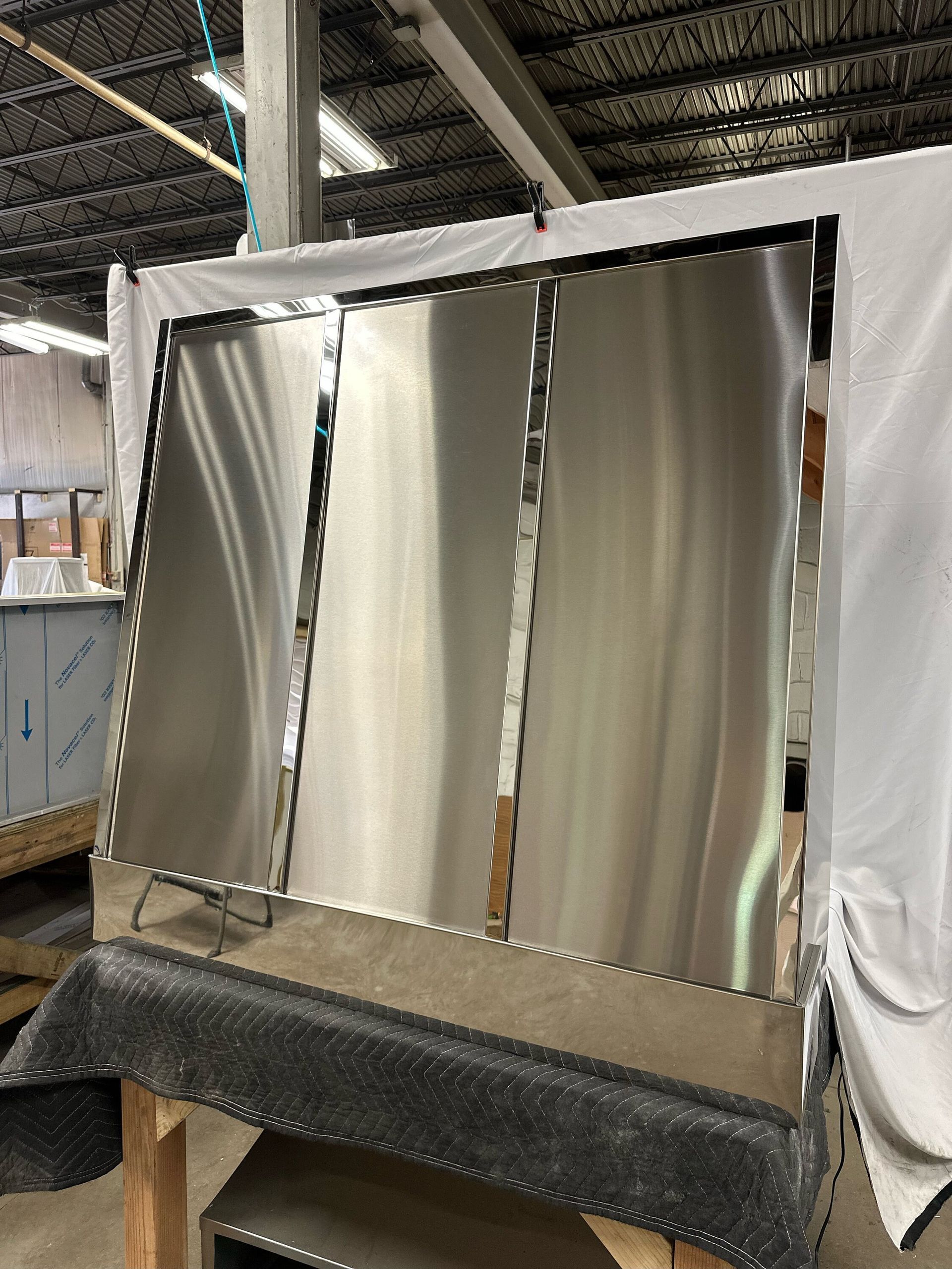 Metal panels in a warehouse display booth, framed in white with a black speckled base