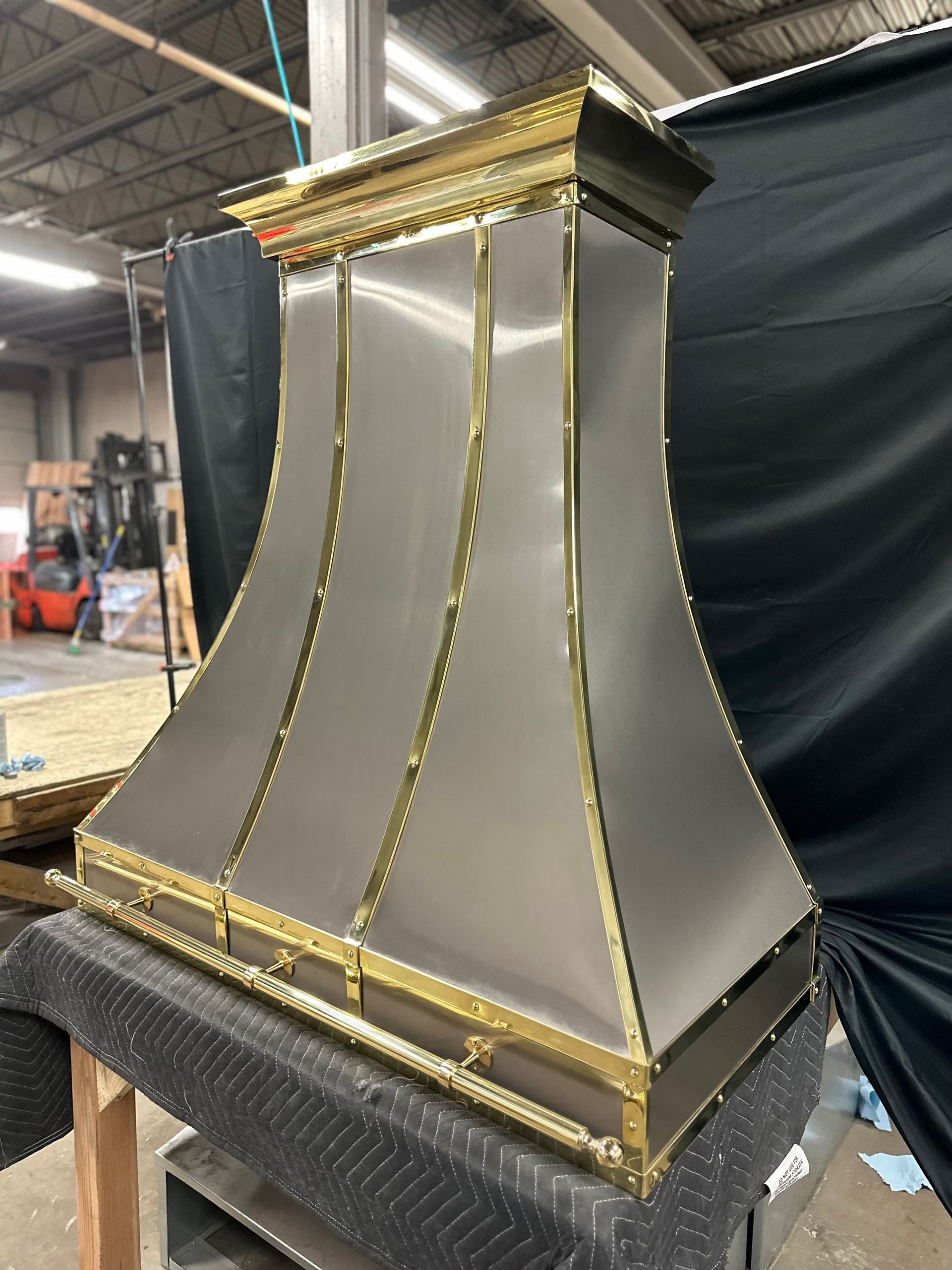 Decorative gold-and-silver column or pedestal in a workshop, with black backdrop.