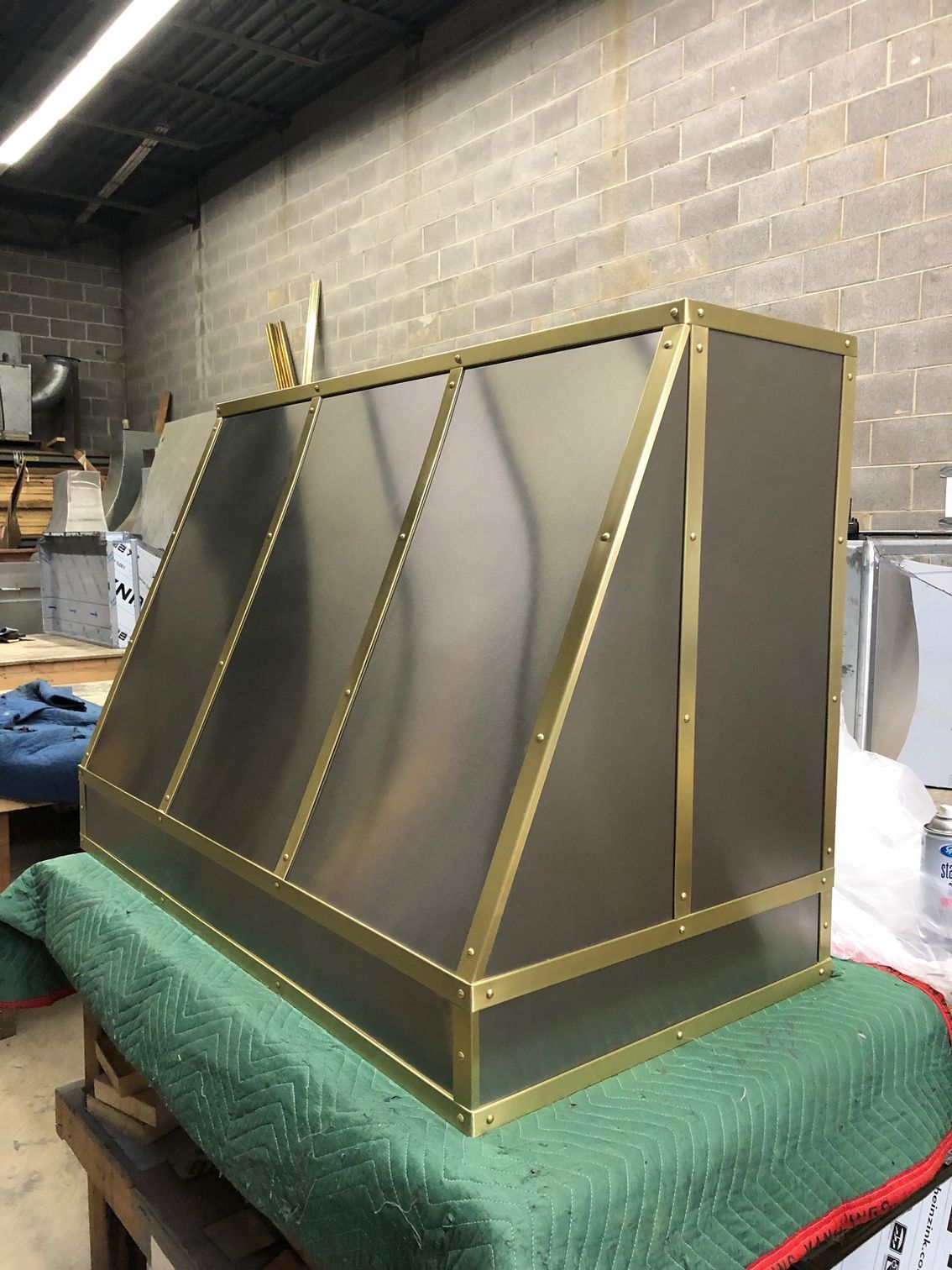 Brass-framed metal structure on a green-covered pallet in an industrial workshop
