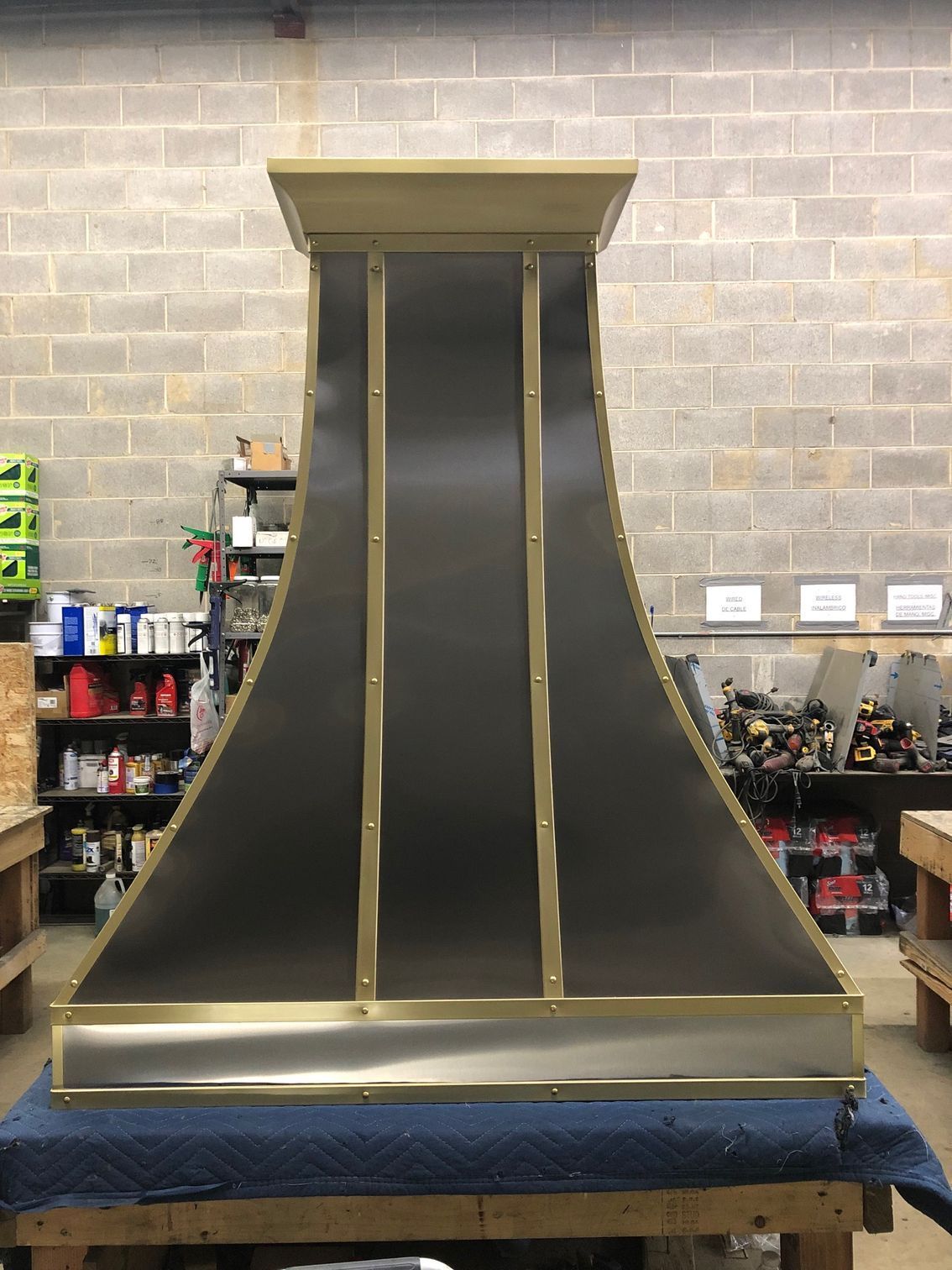 Large black-and-gold ramp or chute display in a workshop, viewed front-on against a cinderblock wall.