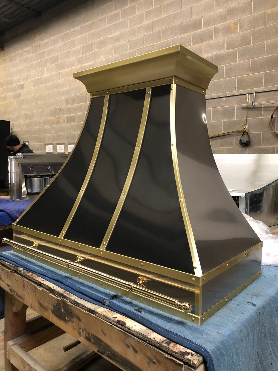 Black-and-gold decorative vent hood on a workbench in a workshop
