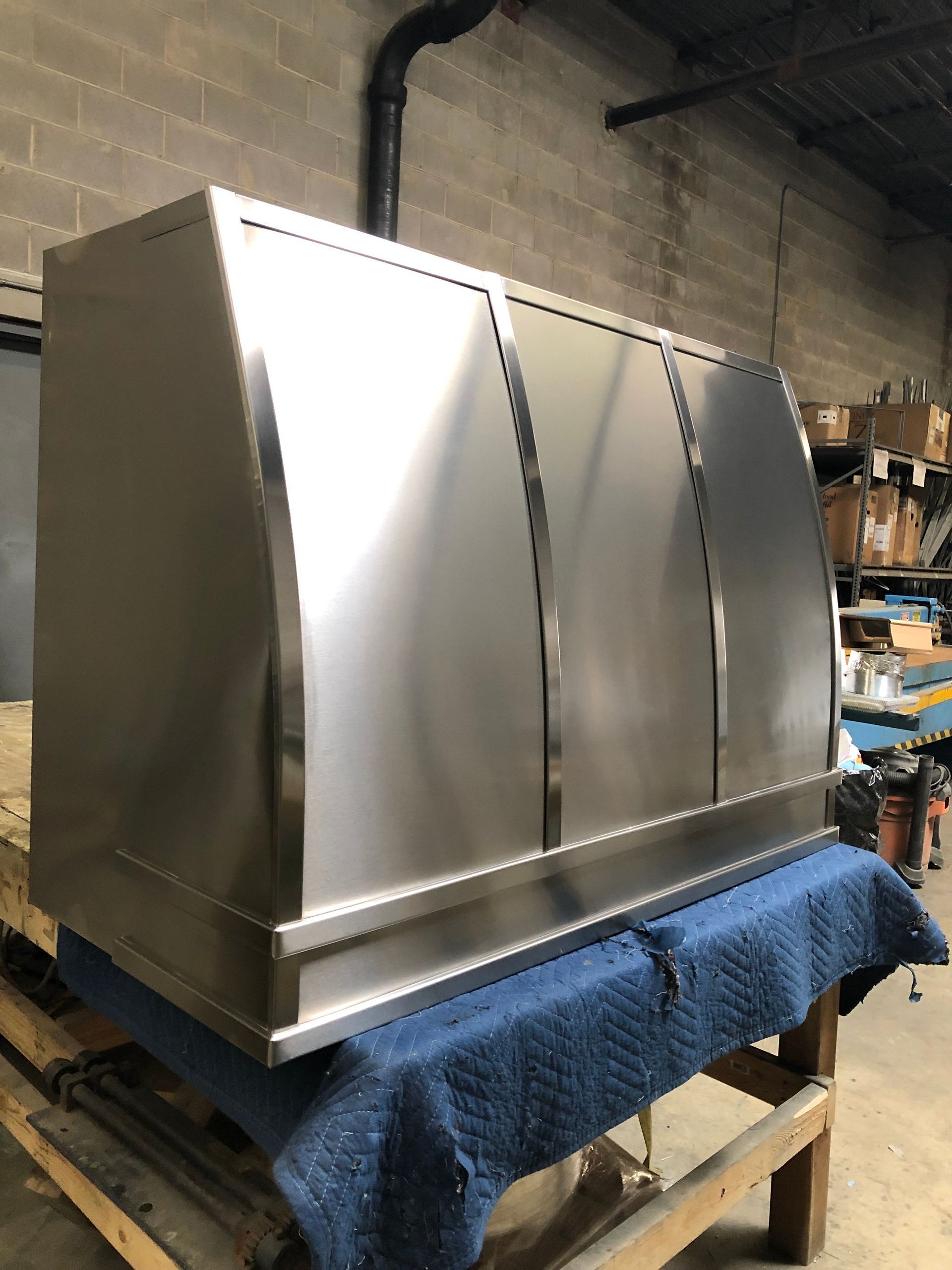 Stainless steel industrial hood on a workbench in a warehouse
