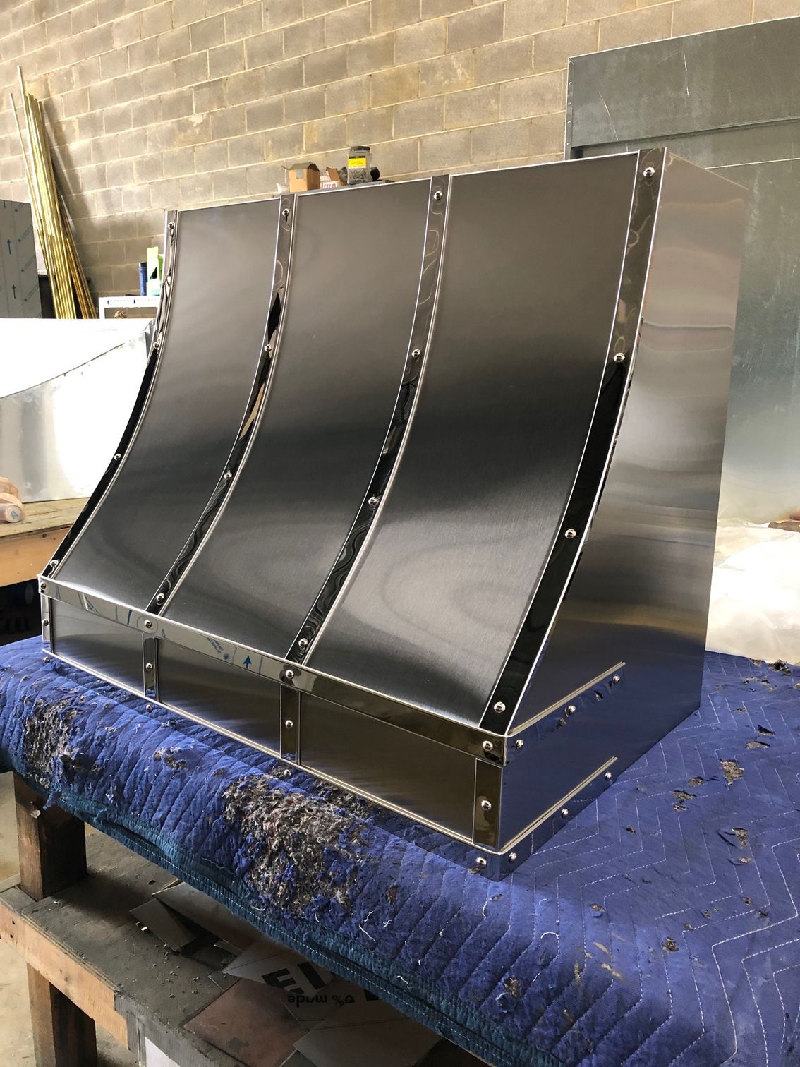 Black metal panel with three curved sections on a workbench in a workshop