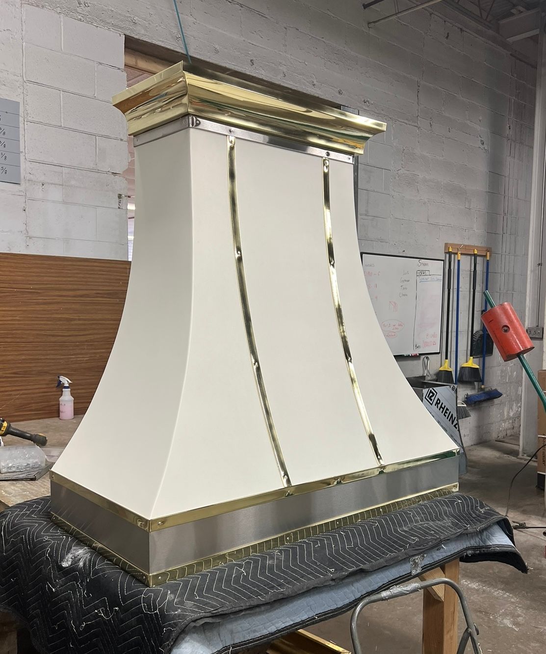 Large cream-and-gold decorative column or pedestal in a workshop on a covered platform