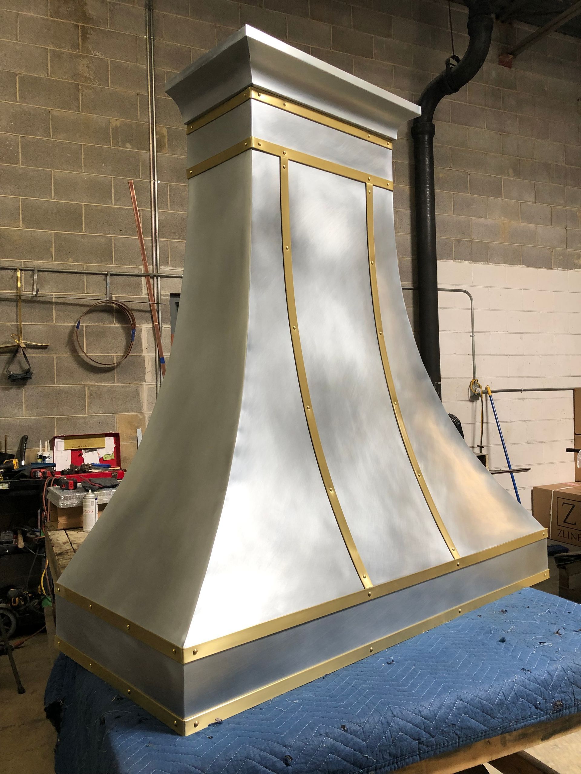 White and gold decorative vent hood on a blue worktable in an industrial workshop