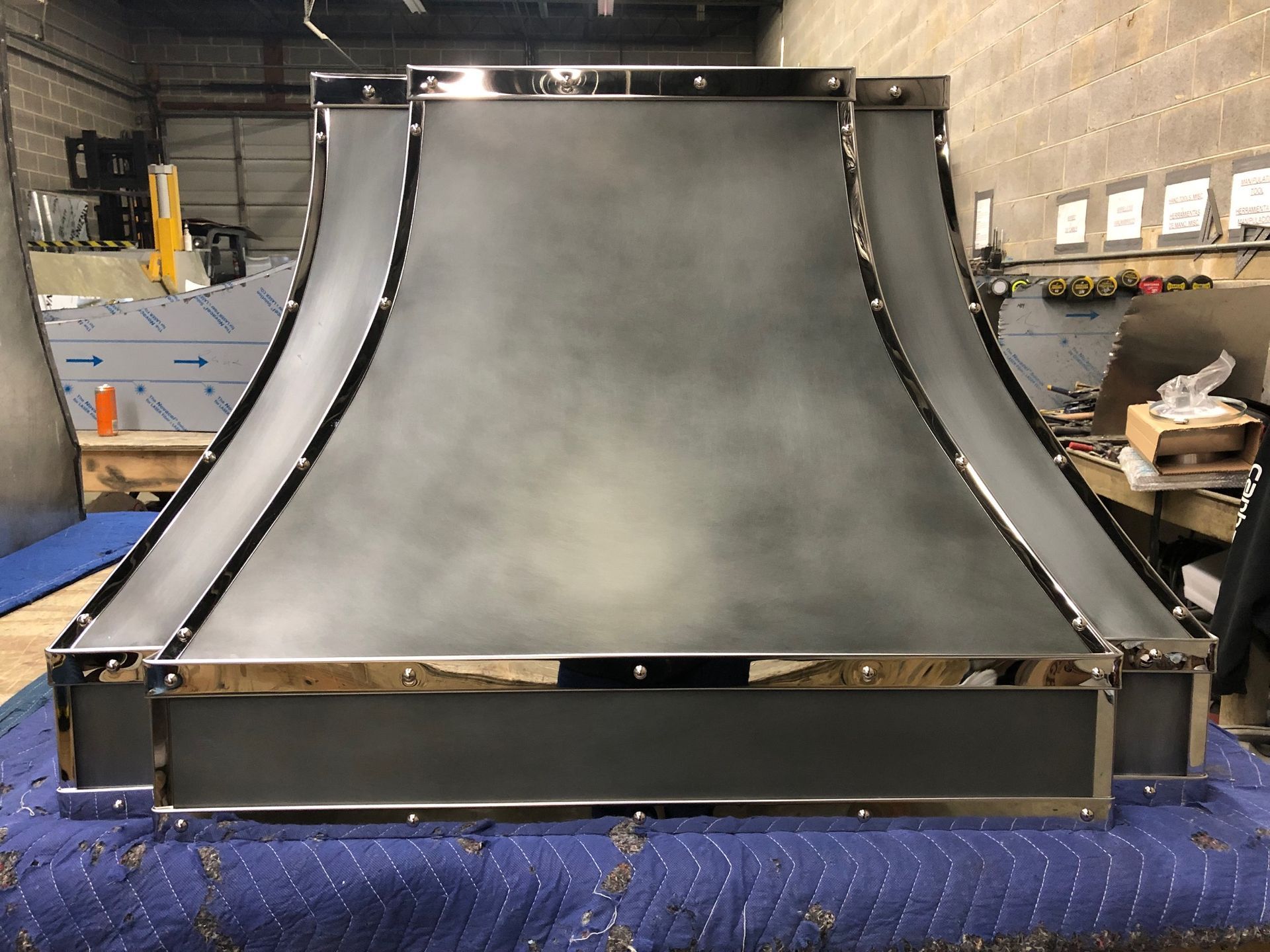 Large gray curved metal ramp structure in an indoor workshop, viewed from the front