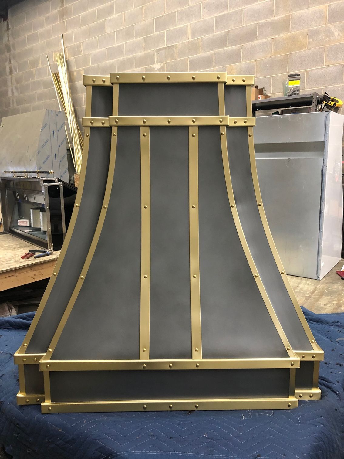 Large black-and-gold curved structural panel standing in a workshop against a brick wall