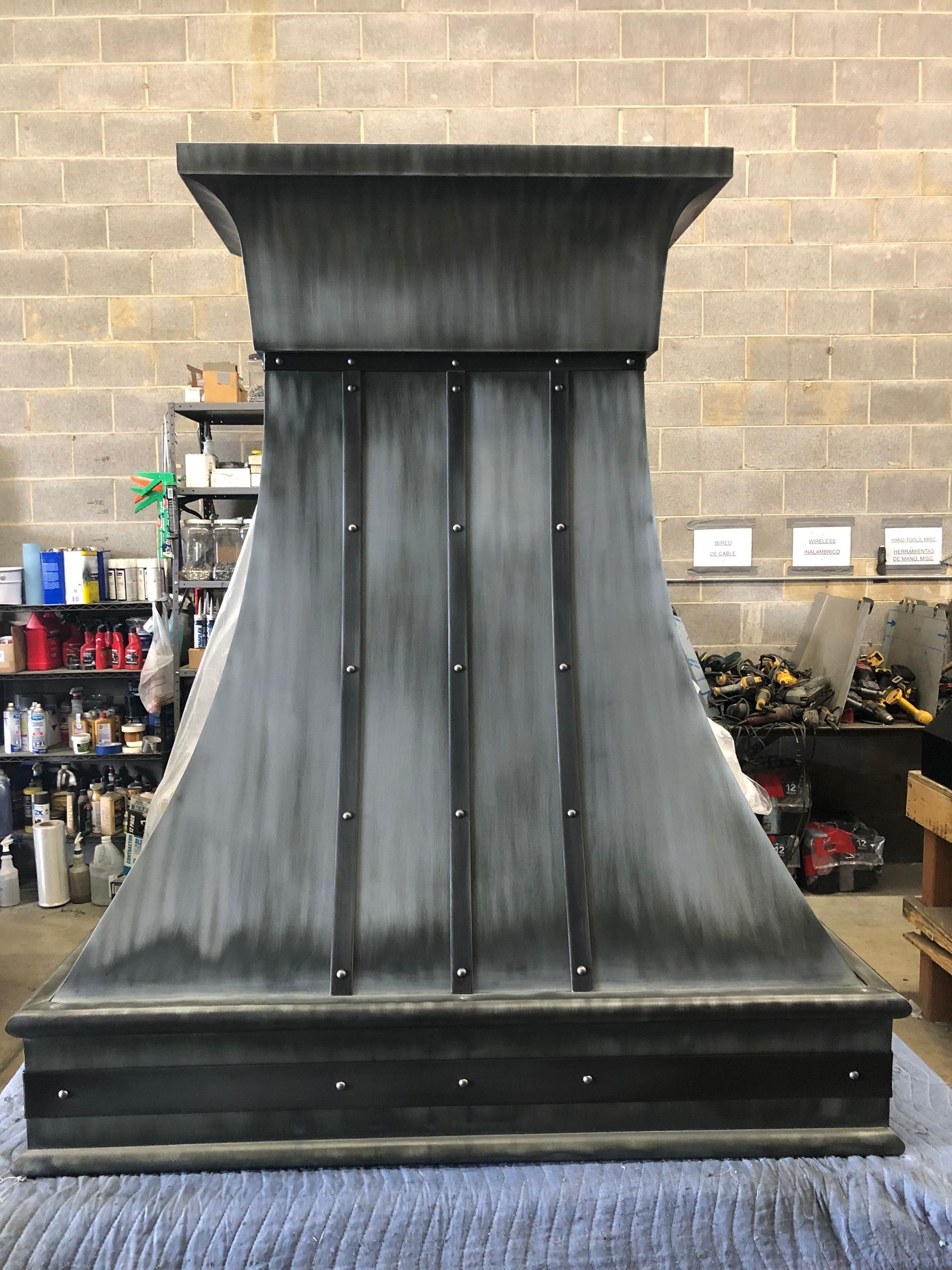 Large black metal fireplace hood or chimney surround in a workshop setting