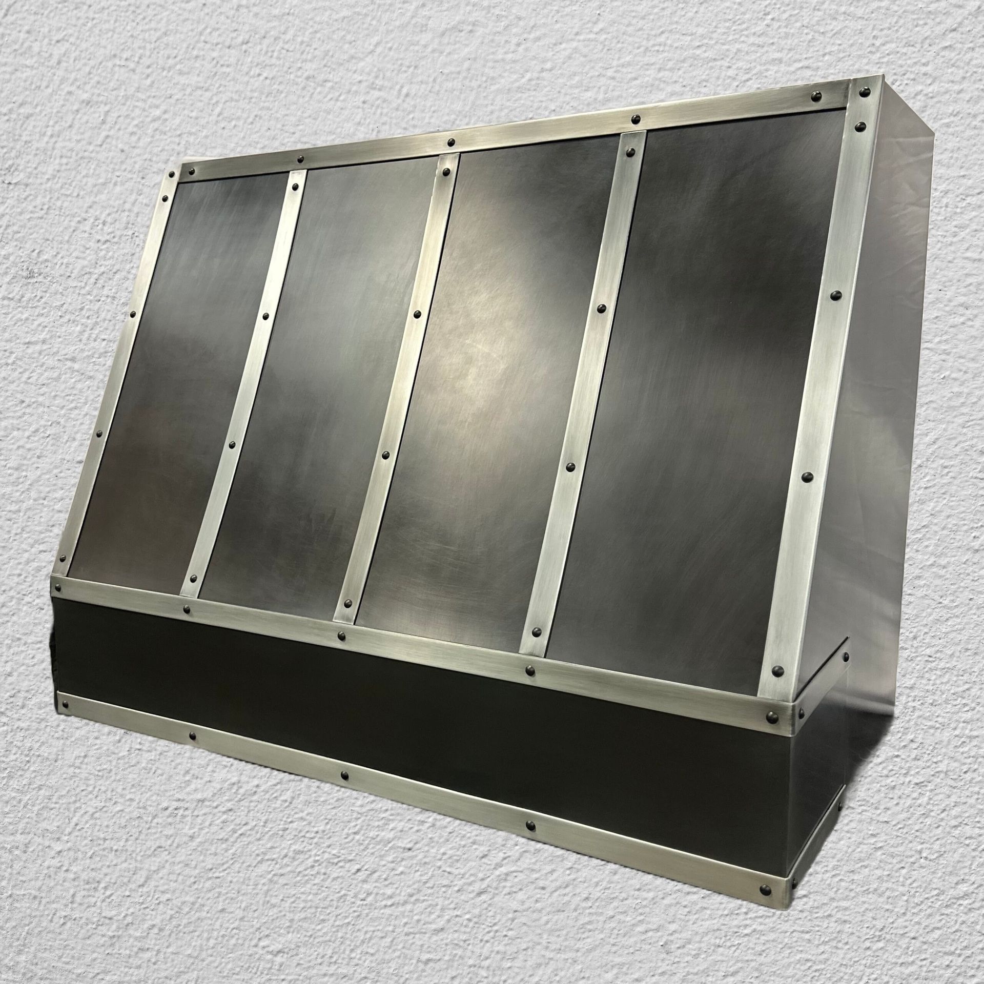 Wall-mounted stainless steel vent hood with angled panels and a black lower section