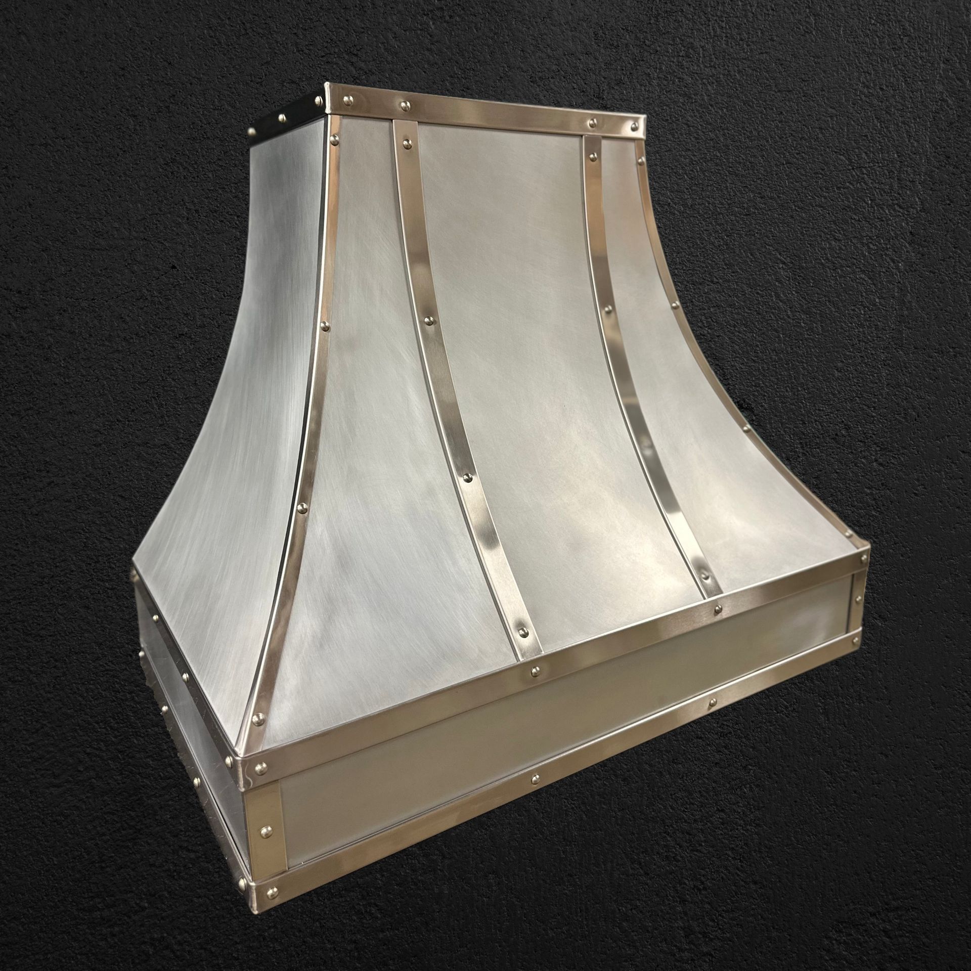 Stainless steel industrial hood vent with curved panels on a dark background