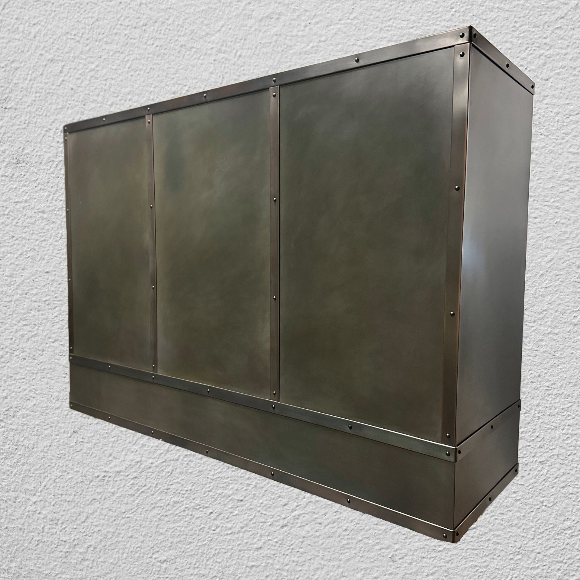 Wall-mounted olive-green metal cabinet or vent box on a white textured wall