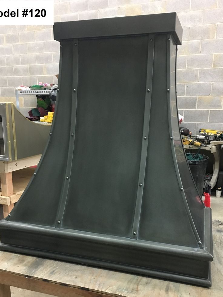 Black metal vent hood on a workbench in a workshop