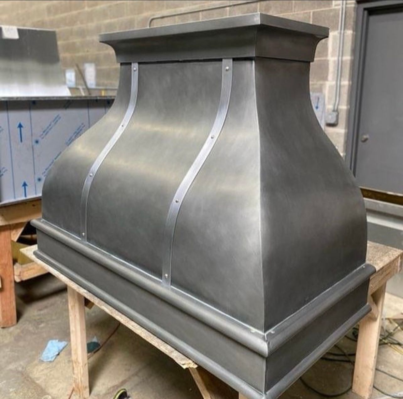 Silver metal ventilation hood on a wheeled cart in a workshop area