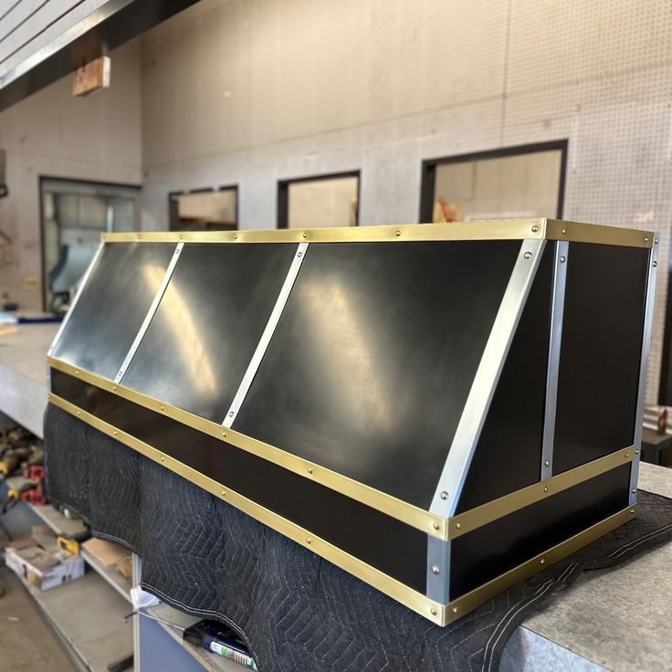 Black metal and gold-trimmed rectangular box on a workshop bench