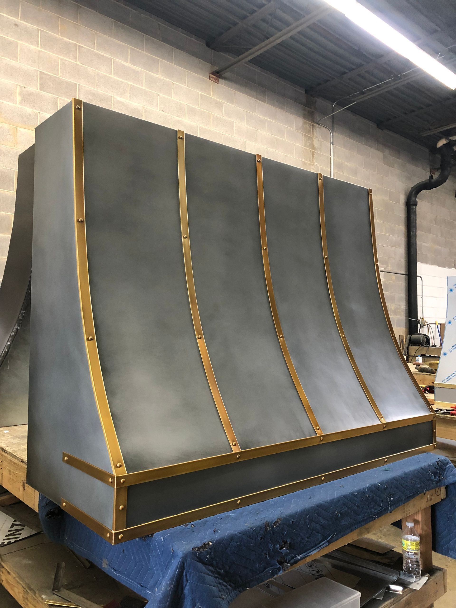 Large gray metal industrial duct or housing with gold seams on a blue pallet in a warehouse