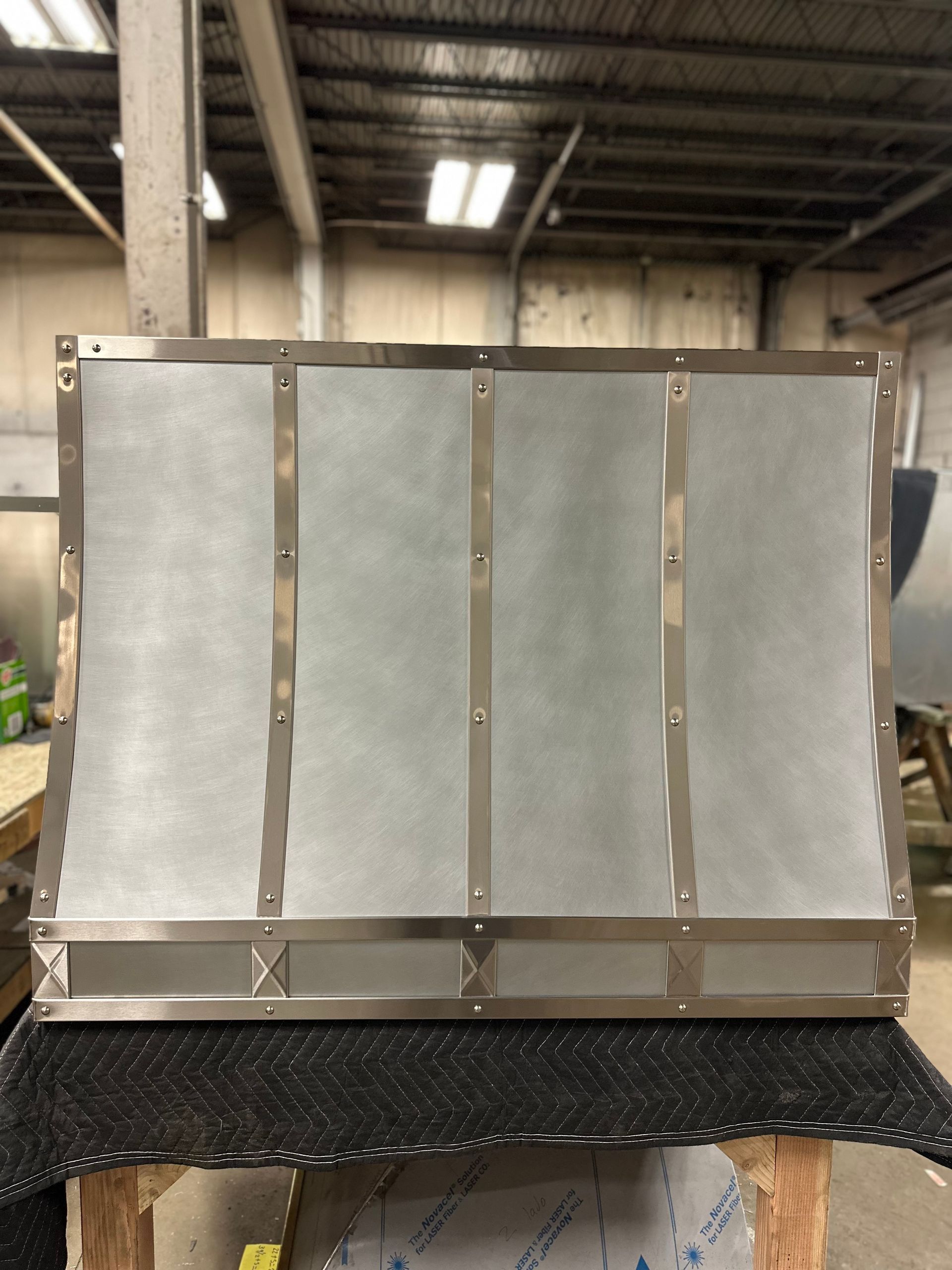 Metal-framed industrial panel with four gray sections on a workbench in a warehouse.