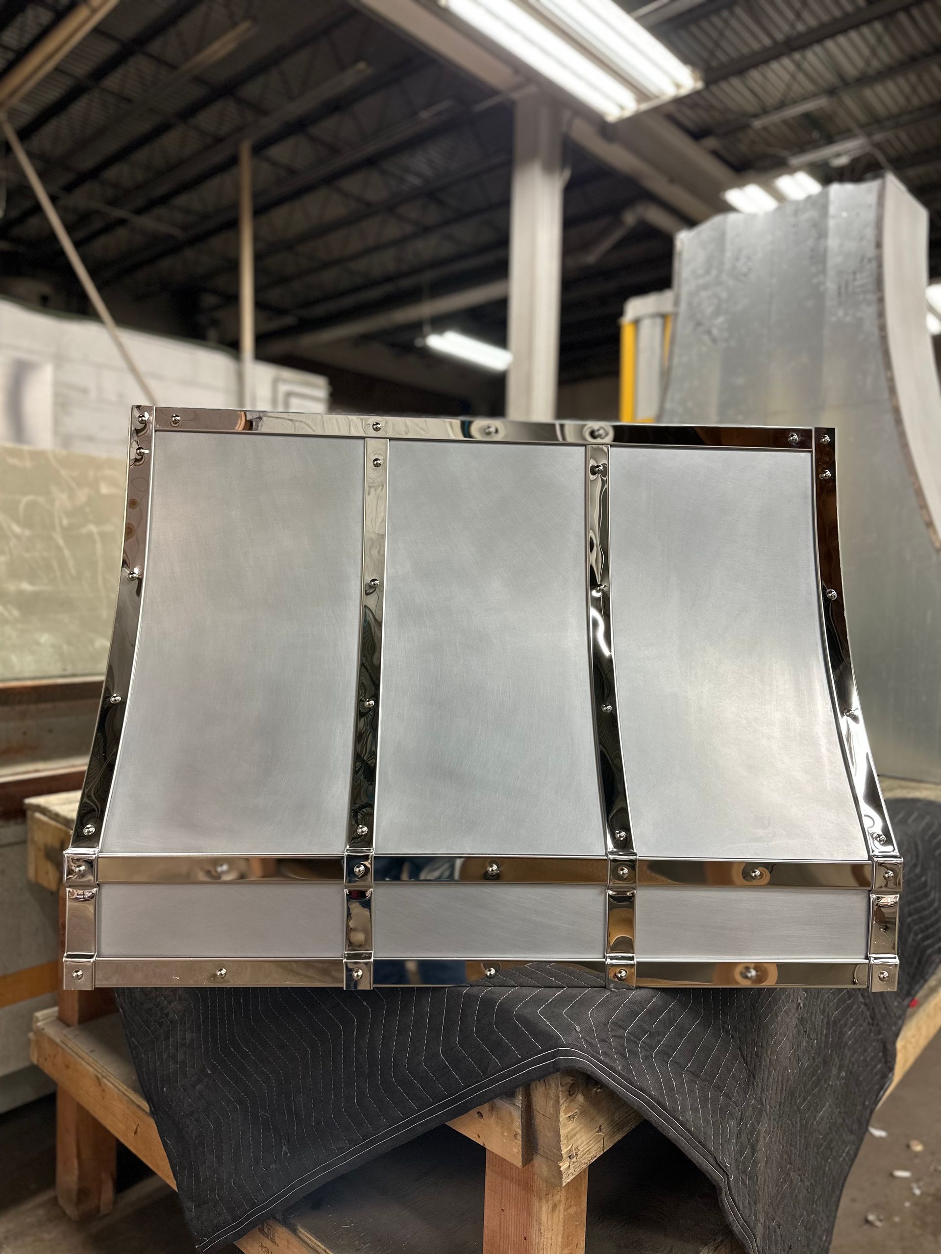 Three shiny metal panels on a workbench in an industrial workshop