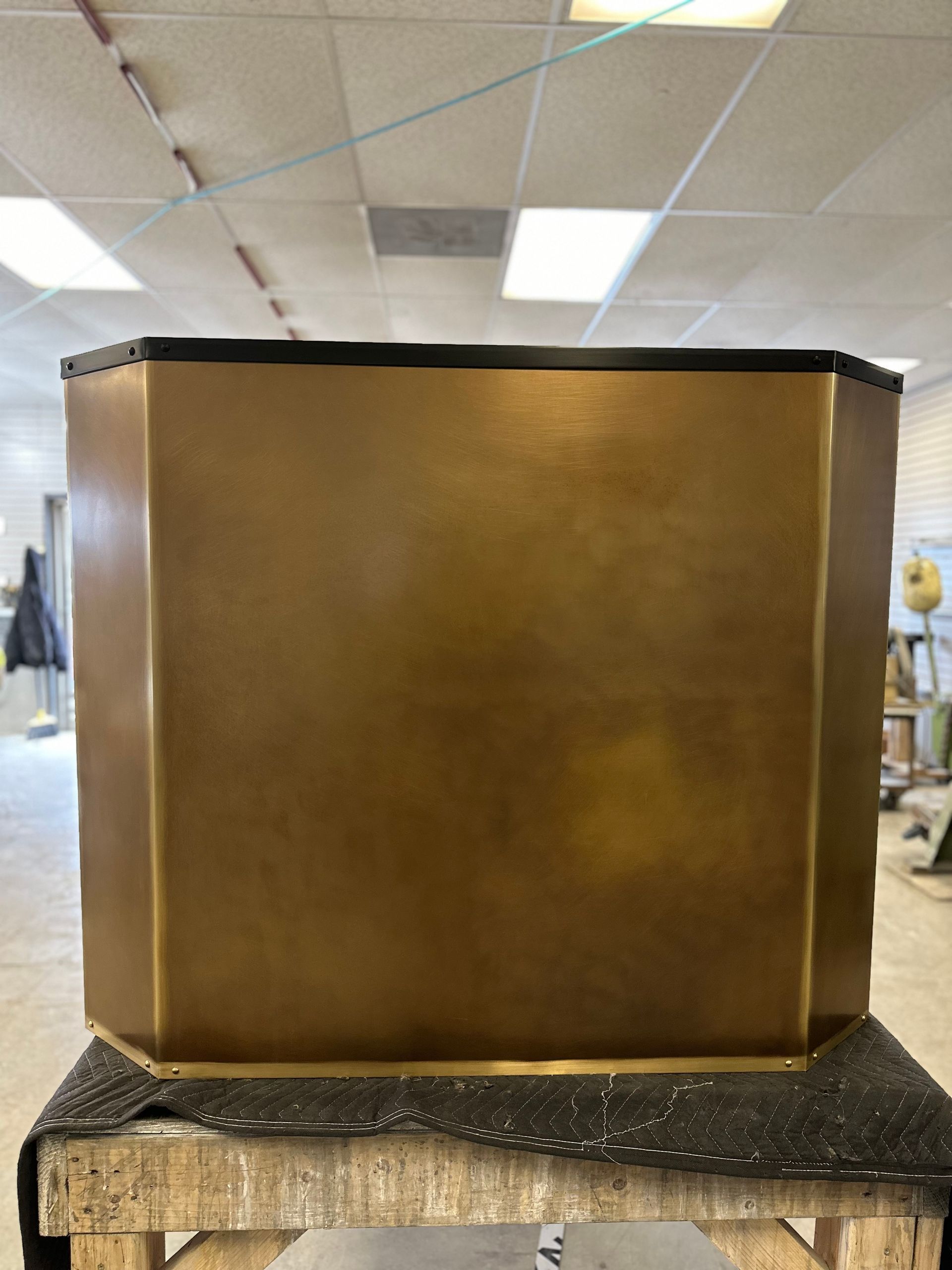 Large brown hexagonal podium on a granite counter in a room with drop ceiling tiles.