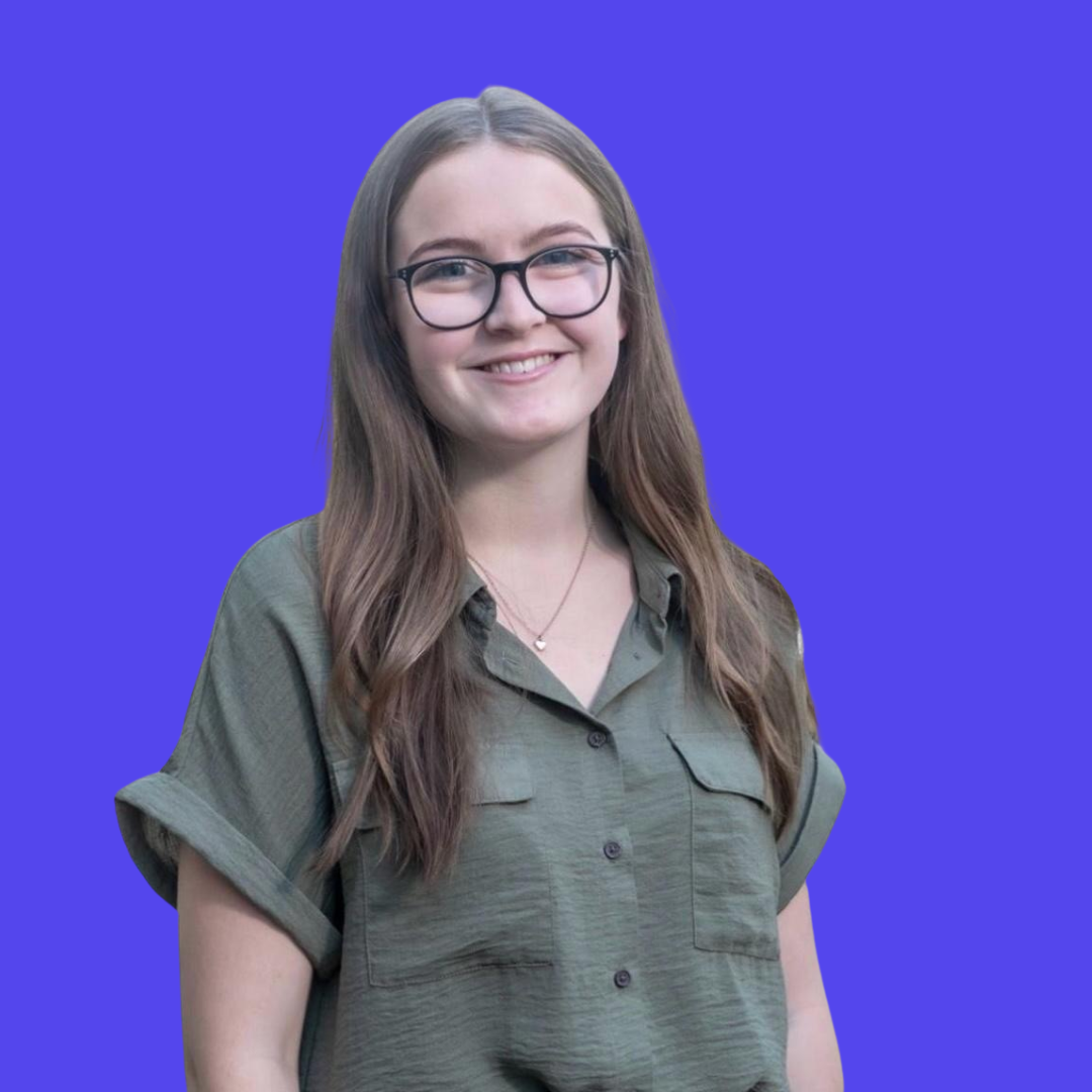 A woman wearing glasses is standing in front of a blue background.