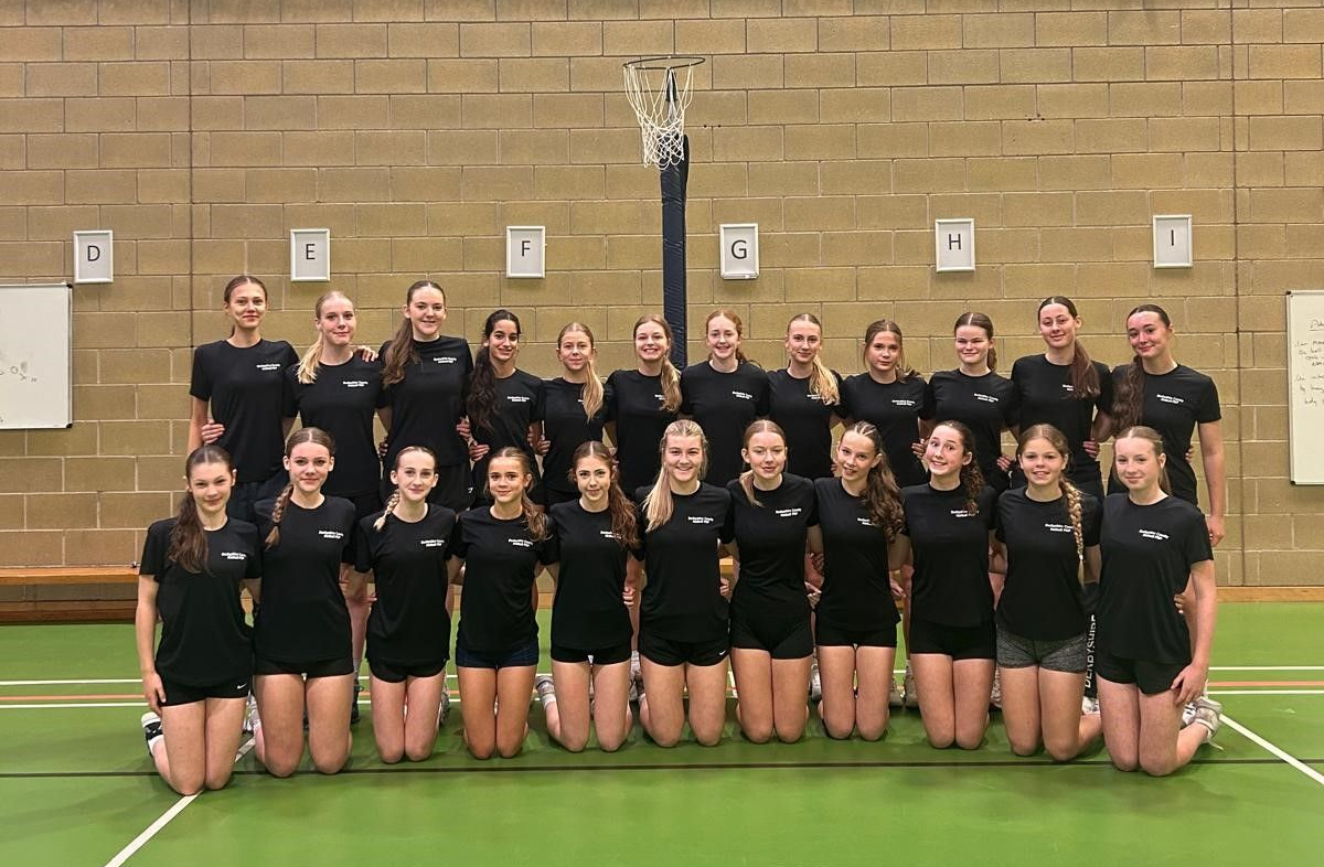 A group of girls are posing for a picture in a gym
