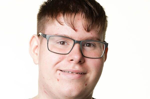 En ung mand iført briller og smiler til kameraet.