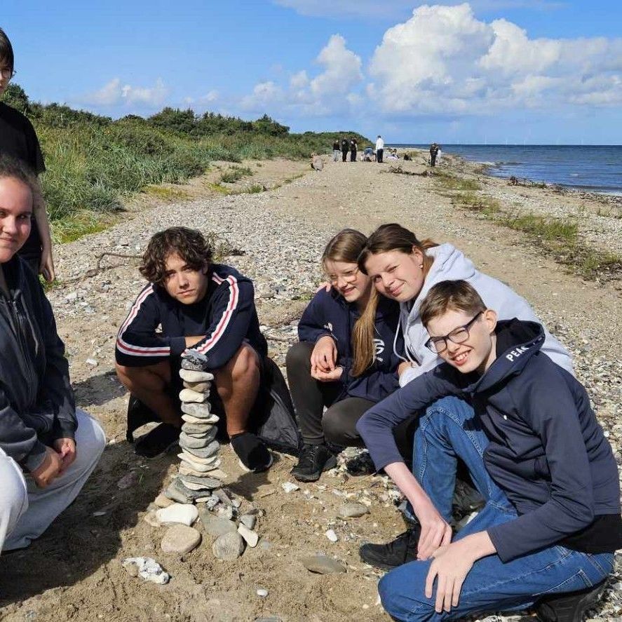En gruppe mennesker poserer til et billede på en strand.