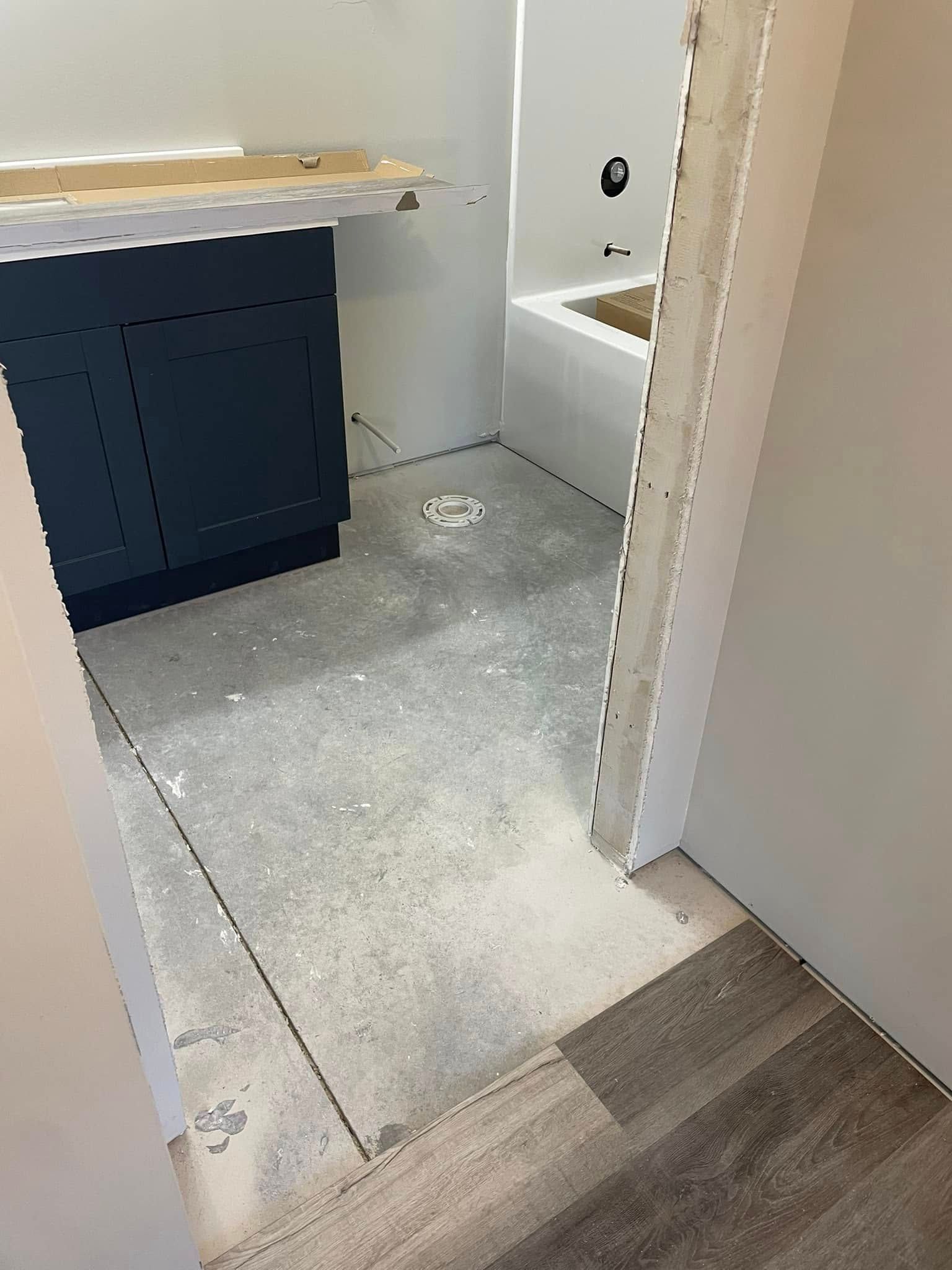 Empty unfinished bathroom with vanity, tiled floor, and wood flooring at the doorway