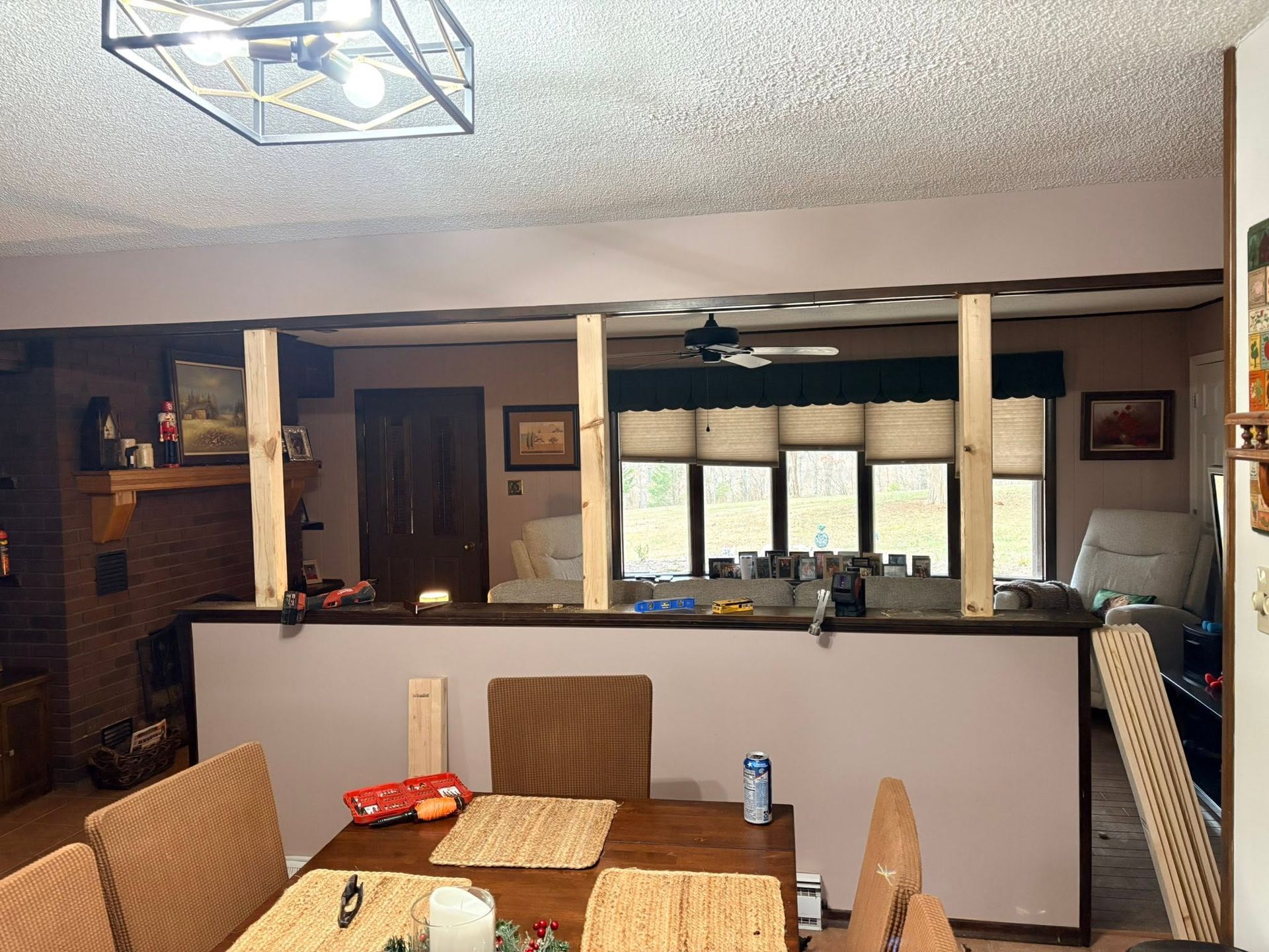 Dining room with glass-top table, wicker chairs, and open view to a kitchen and living area