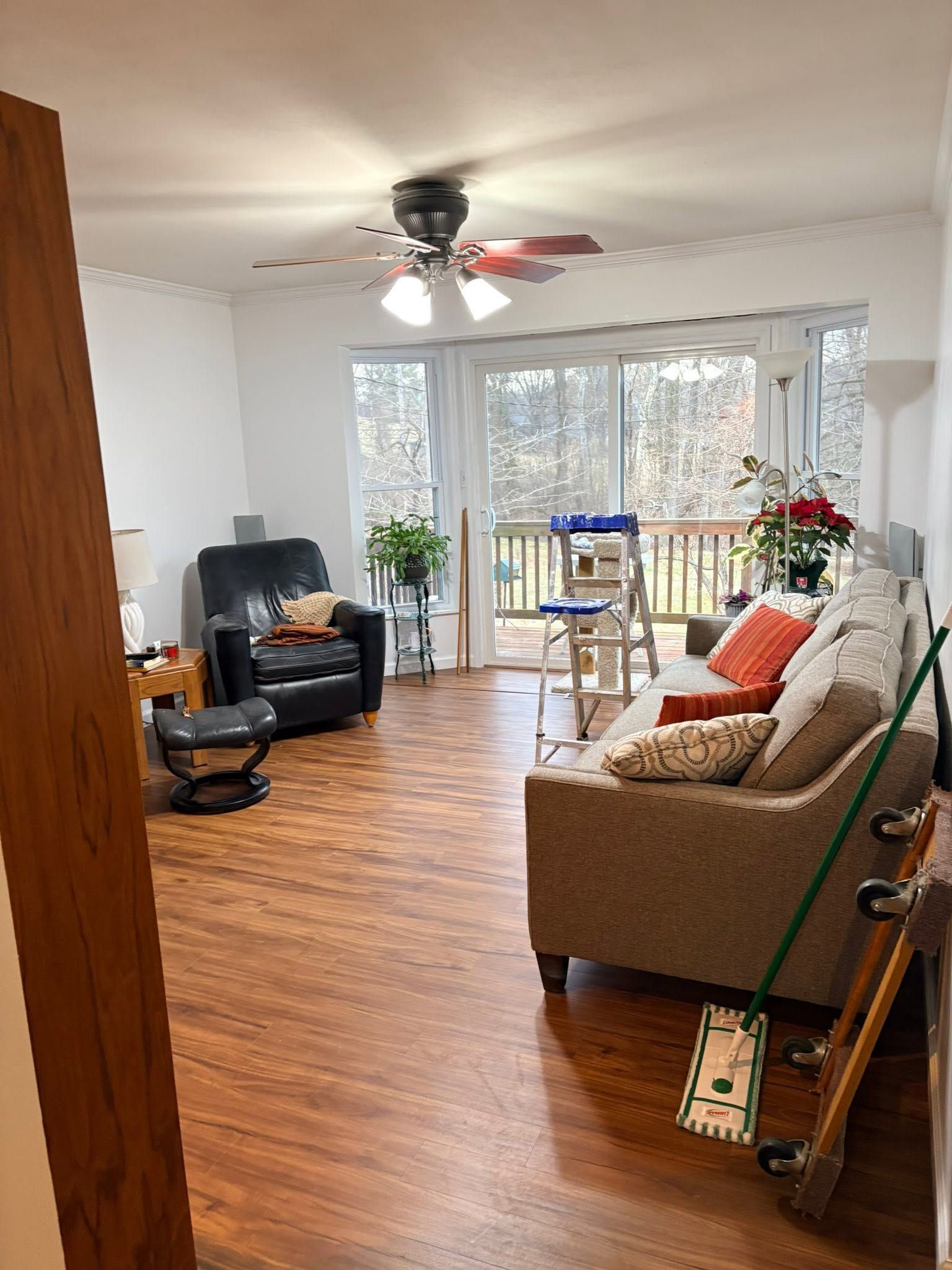 Bright living room with wood floors, sofa, recliner, ceiling fan, and sliding glass doors to a balcony.