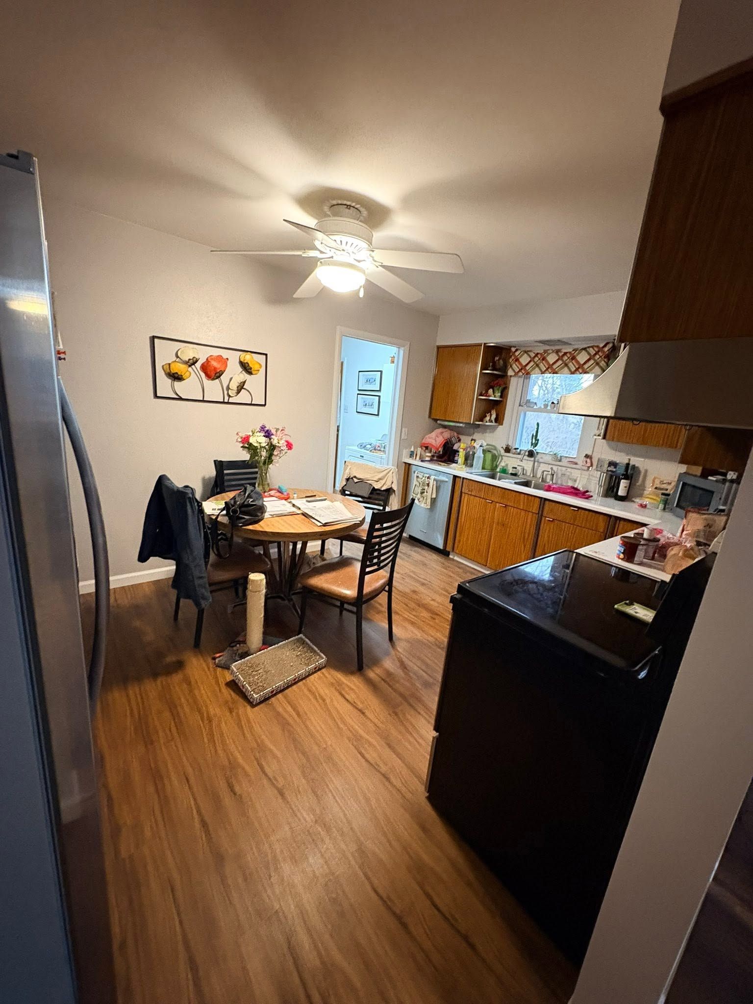 Compact kitchen and dining area with table, chairs, ceiling fan, and warm wood floors