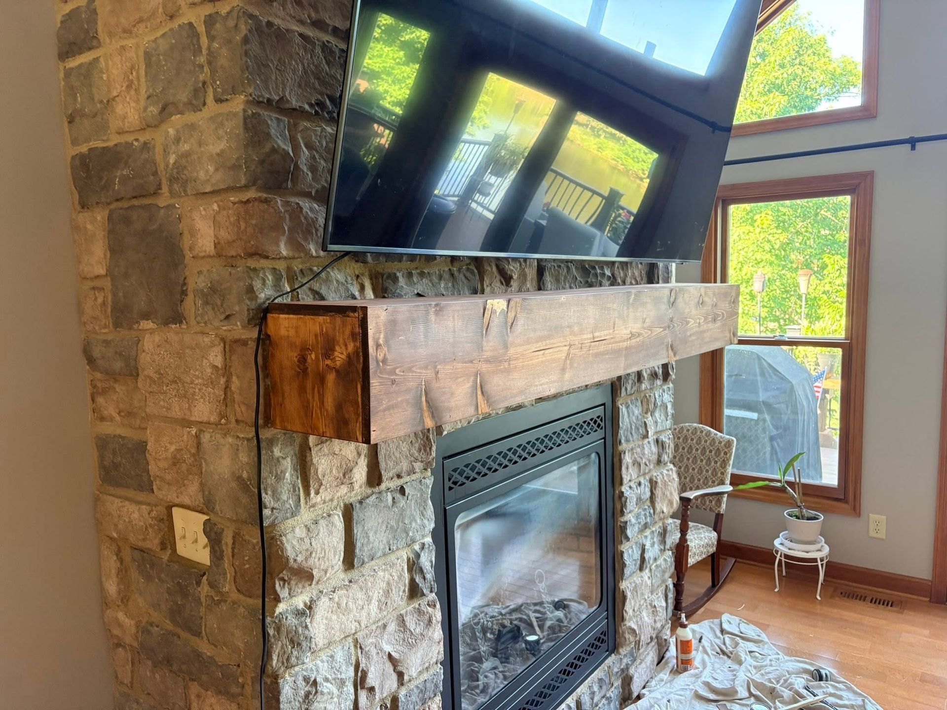 Stone fireplace with mounted TV and bright windows in a sunlit living room