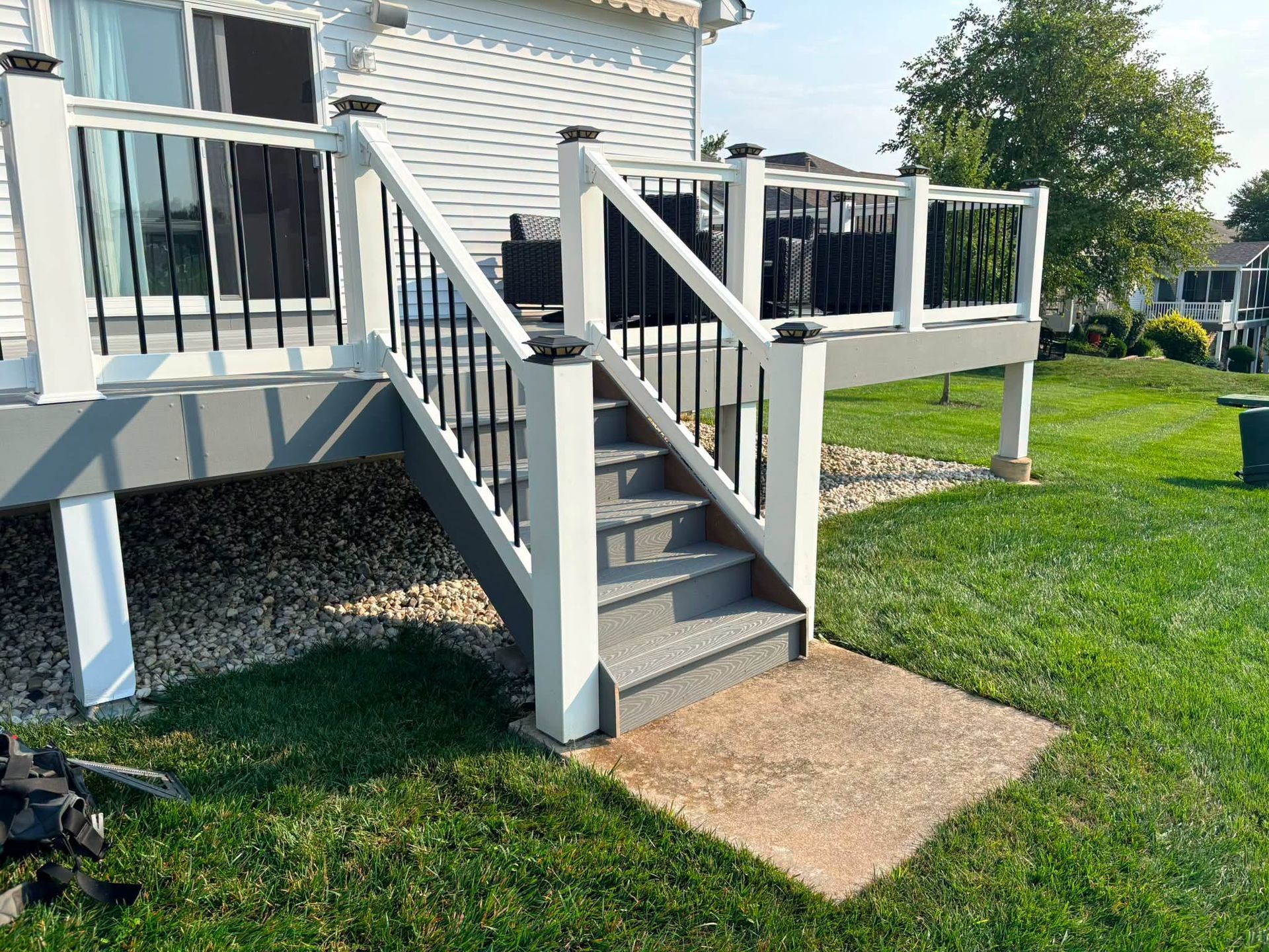 White wooden porch ramp and stairs leading to a house, with a small landing and green lawn.