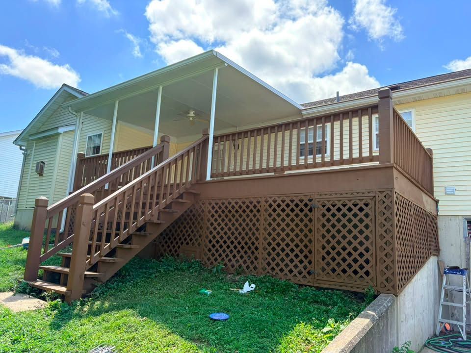 Back wooden deck with stairs and lattice skirting on a house in a grassy yard under a blue sky
