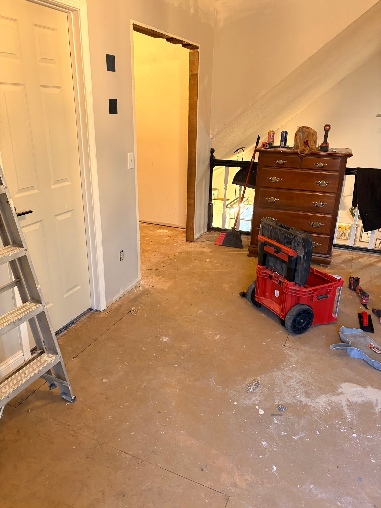 Messy room with open door, ladder, dresser, and red toy truck on the floor