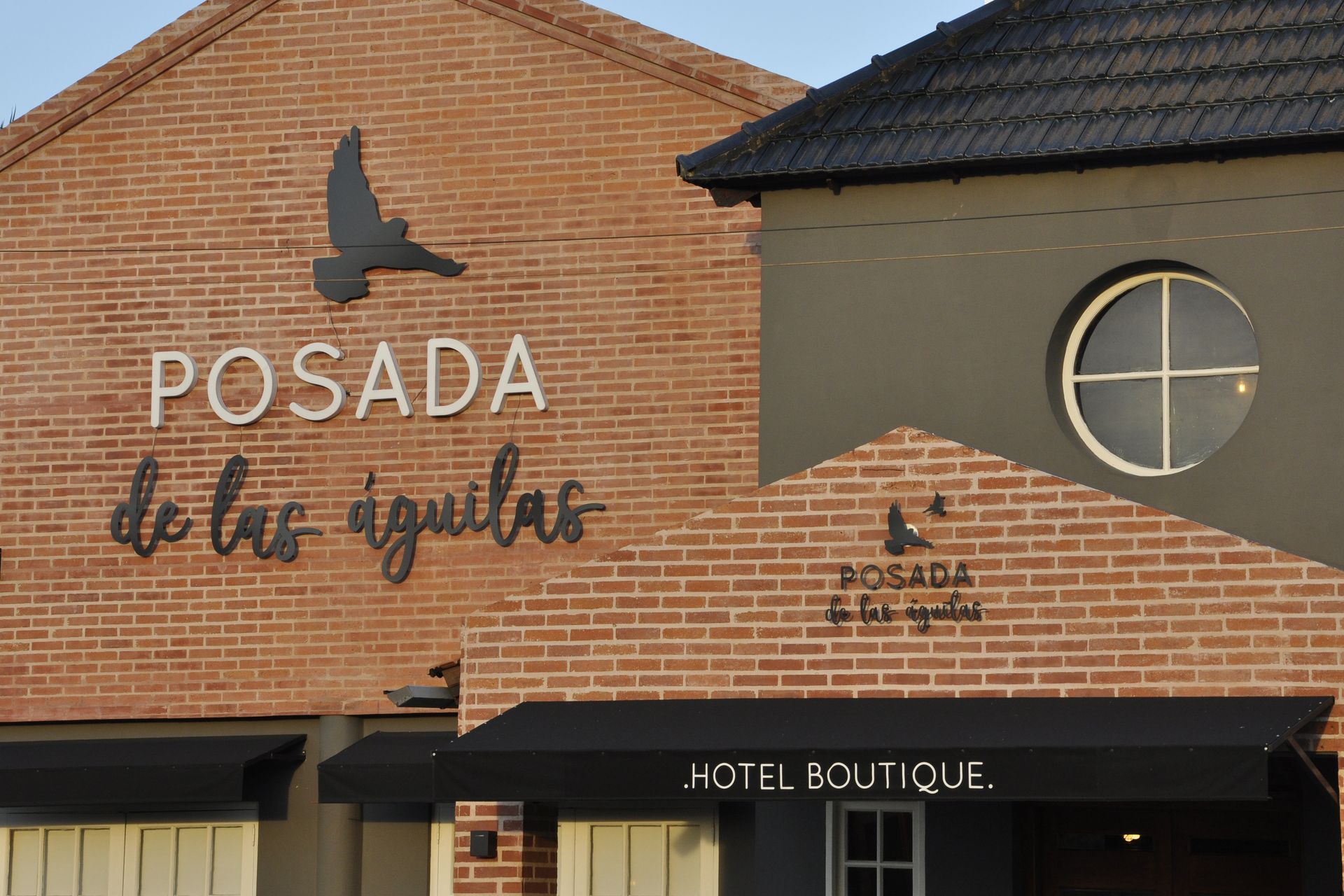 Letrero de “Posada de los Ángeles” en un edificio de ladrillo con logotipo de pájaro.