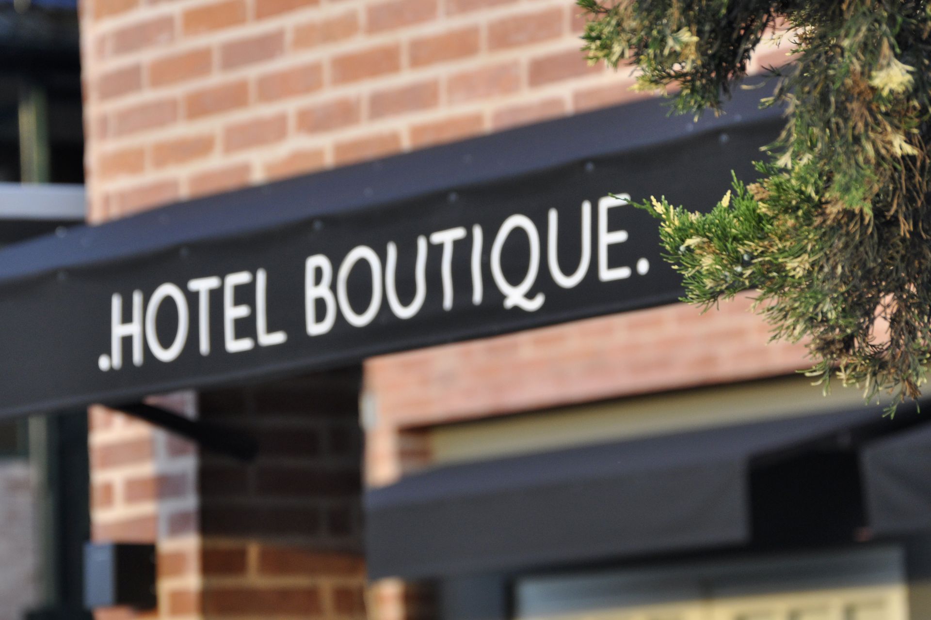 Toldo negro con la inscripción “HOTEL BOUTIQUE” en texto blanco sobre la fachada de un edificio de ladrillo.