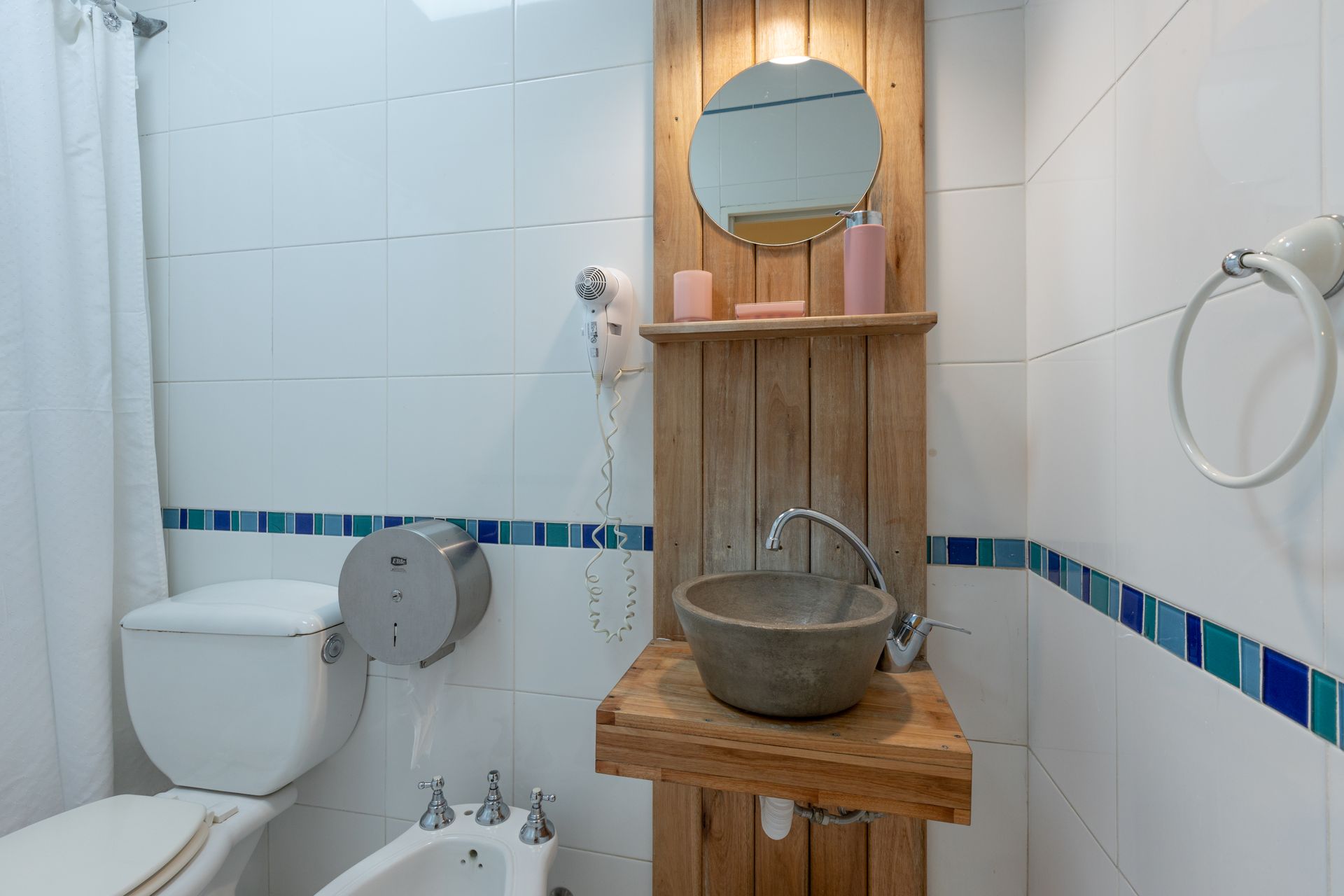 Baño pequeño con inodoro, lavabo, ducha y tocador de madera con espejo y lavabo.