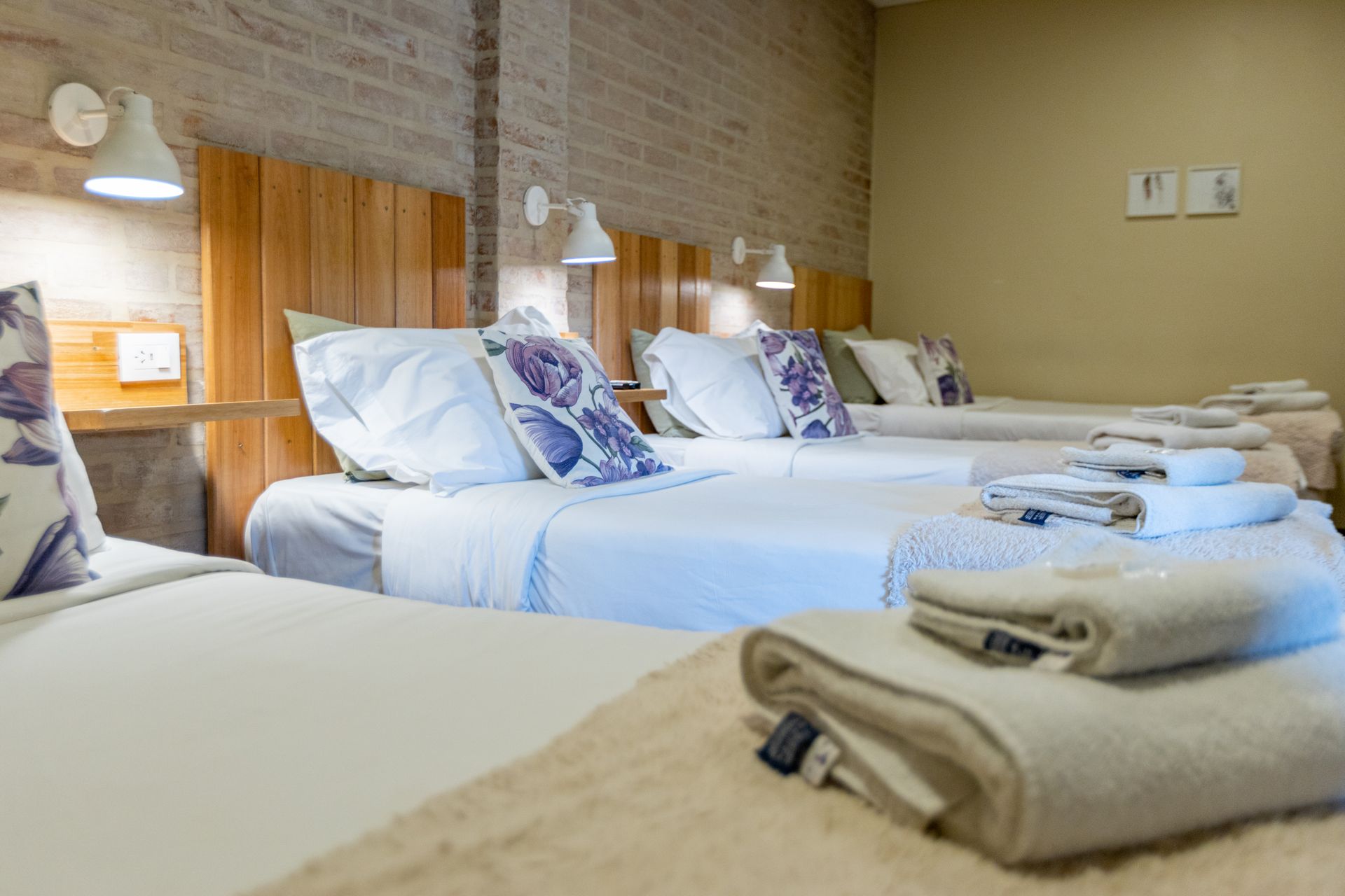 Acogedora habitación de hotel con dos camas individuales, sábanas blancas, toallas dobladas y lámparas de noche que proporcionan una luz cálida.
