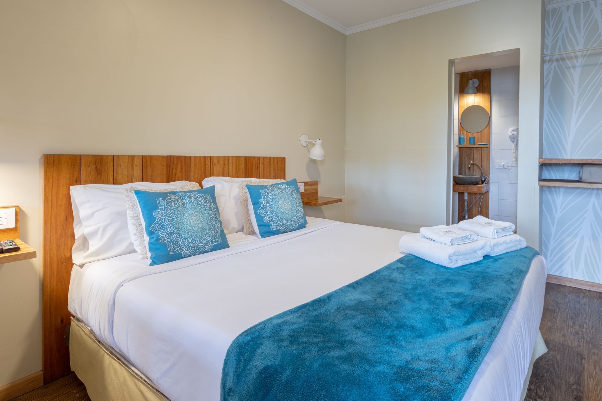 Cama bien hecha con detalles azules en una habitación de hotel de color beige.