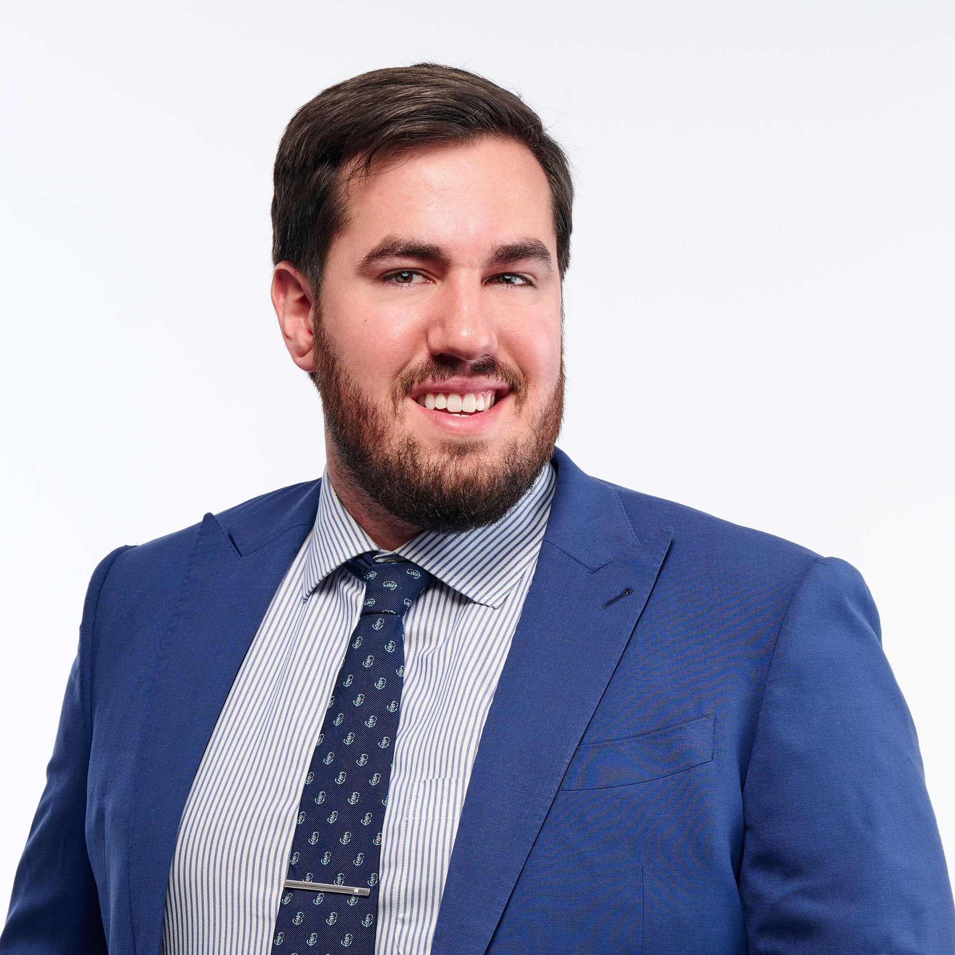 A man with a beard is wearing a blue suit and a watch.