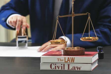 A man is stamping a document in front of a scale of justice.
