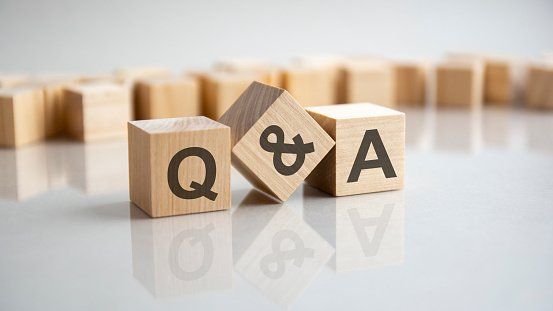 Three wooden blocks arranged on a white reflective surface, spelling