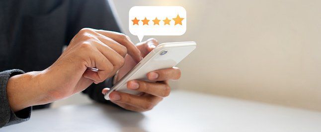 A person uses a smartphone to give a five-star rating, depicted by a floating speech bubble with five filled stars.