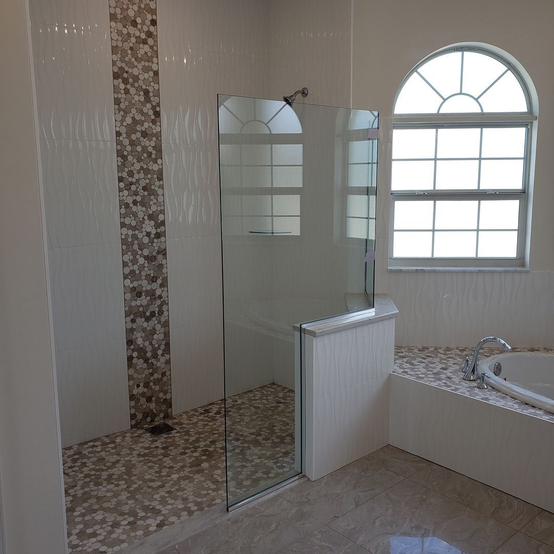 A bathroom with a walk in shower and a tub