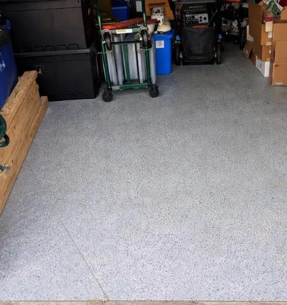 Garage floor with gray speckled coating, storage boxes, carts, and tools along the sides