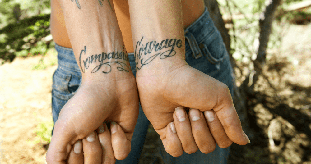 A woman has a tattoo on her wrist that says `` courageous courage ''.